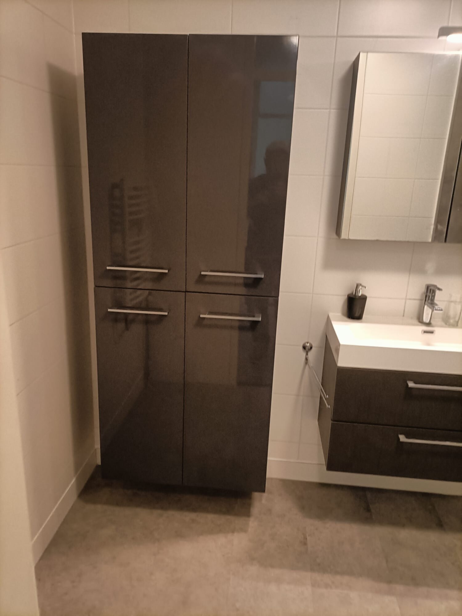Moderne badkamer met donkere kasten en witte tegelwanden