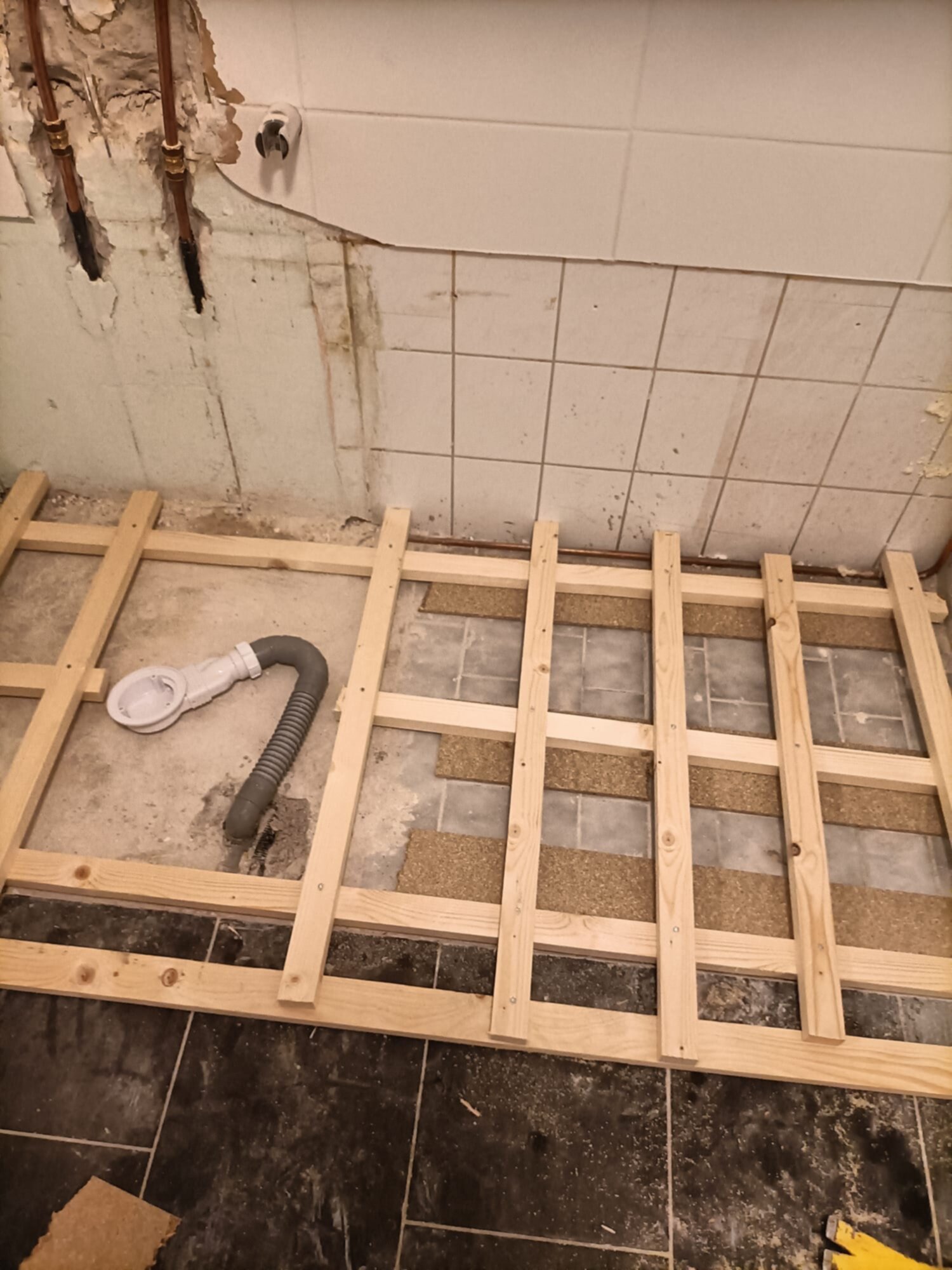 Renovatie van badkamer vloer met houten ondervloer en open leidingen