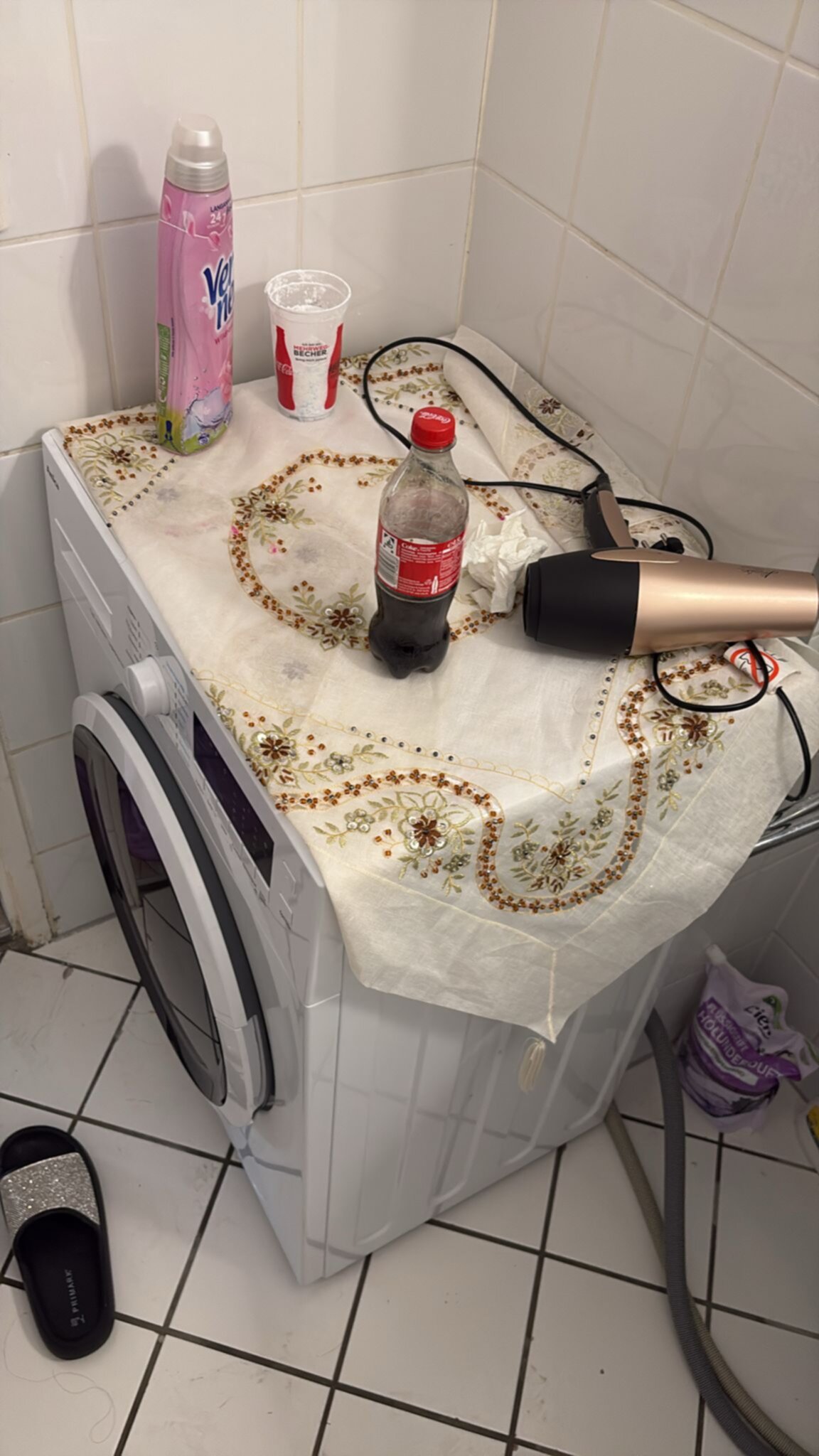 Wasmachine in badkamer met wit tafelkleed en diverse voorwerpen erop