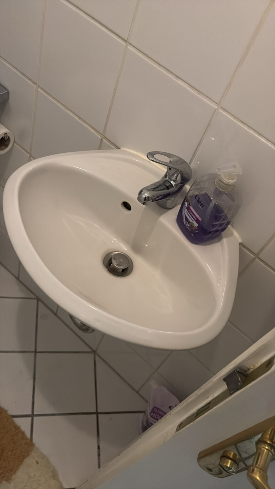 Wit betegelde badkamer met witte wastafel en chroom kraan