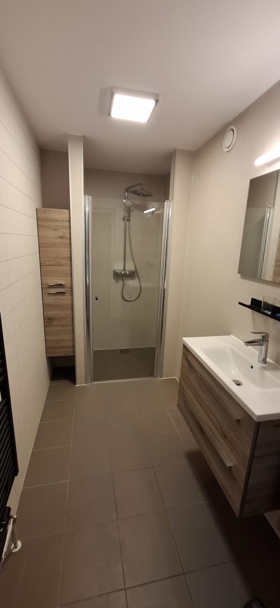 Moderne badkamer met douche, wastafel en houten meubelen in neutrale kleuren