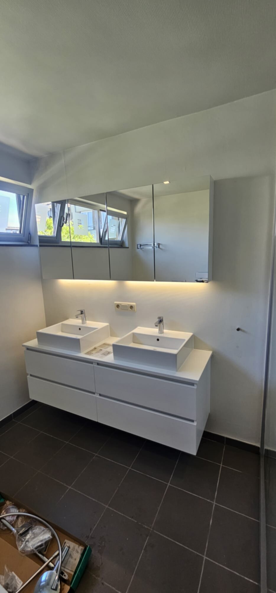 Dubbele wastafel met witte meubels en zwarte tegelvloer in moderne badkamer