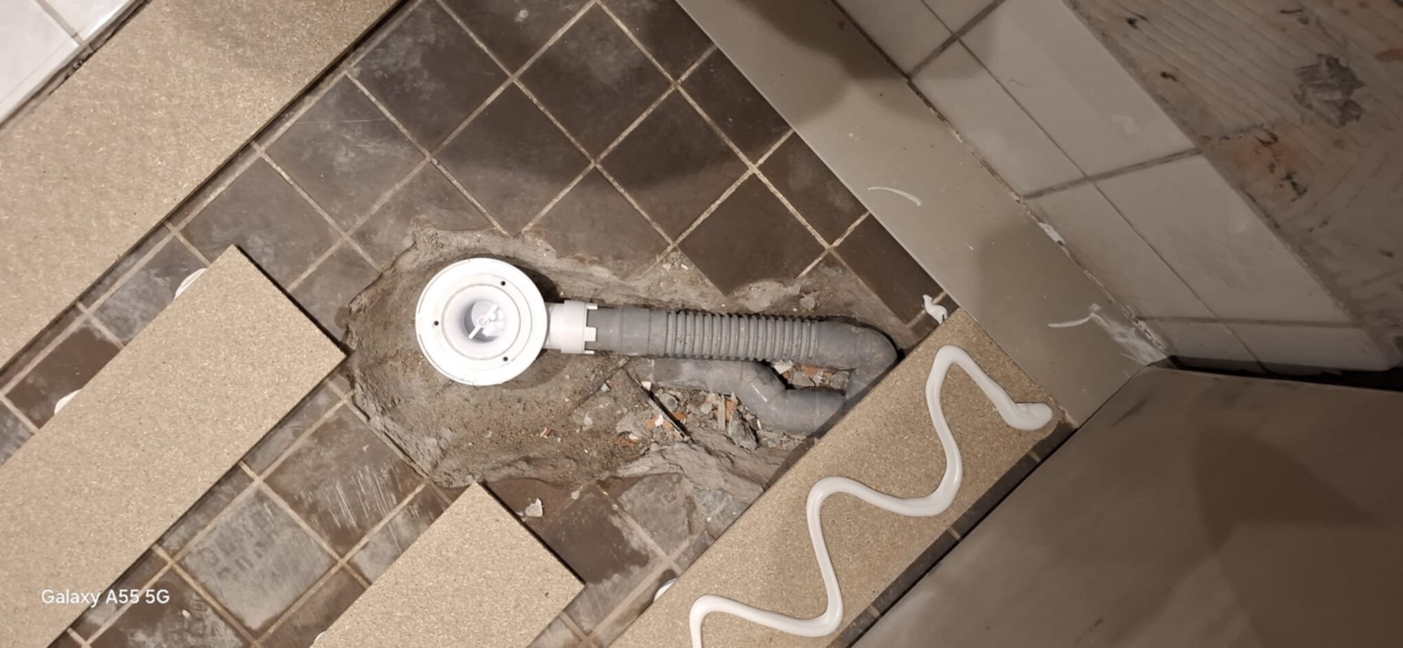 Slijpwerk badkamer vloer met betegelde rioleringsbuis en afvoer