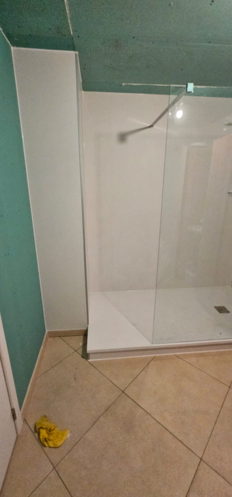 Douchecabine met glazen deur en witte wanden in renovatie fase