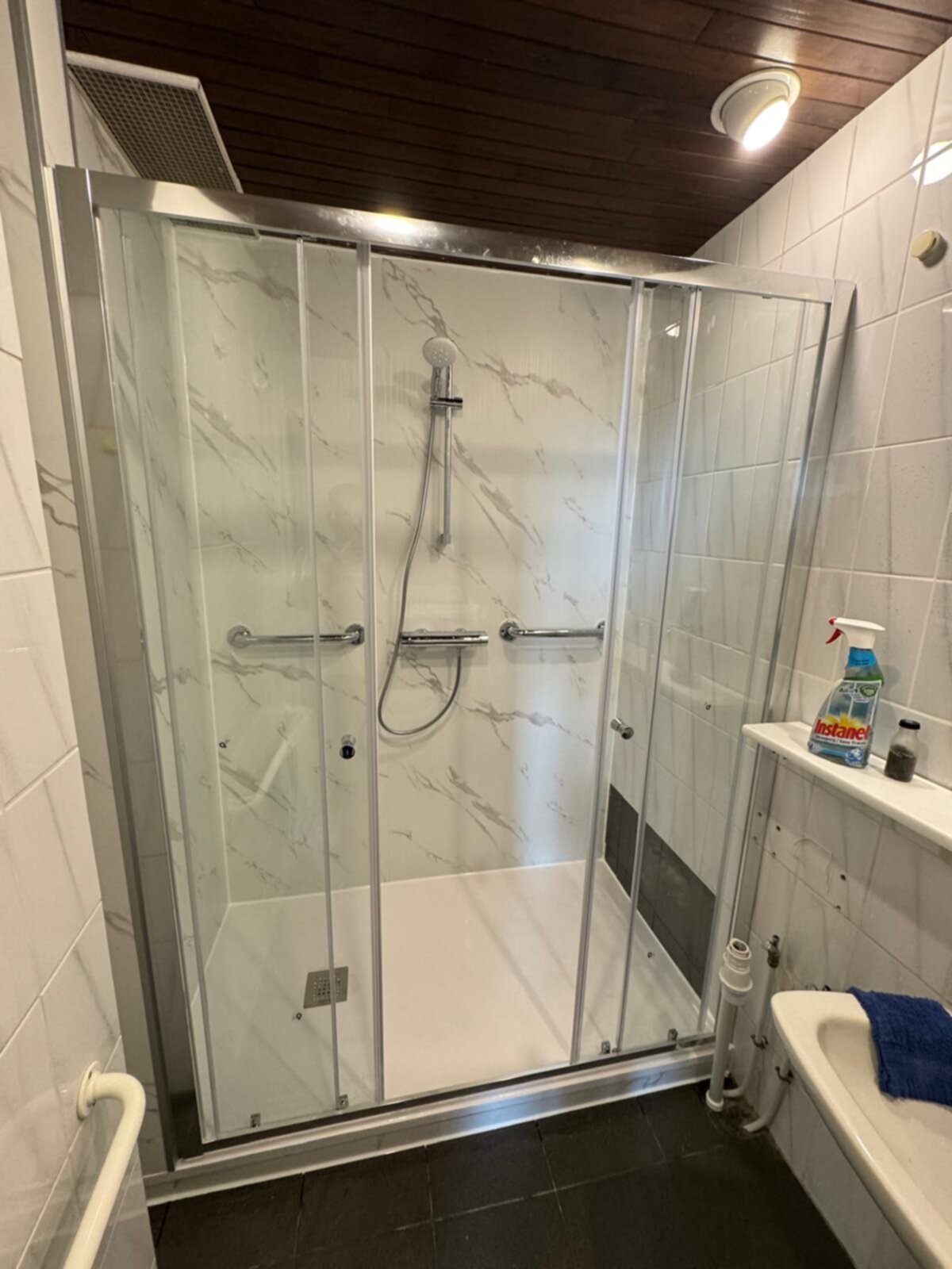 Badkamer met glazen douchecabine en witte marmeren tegels