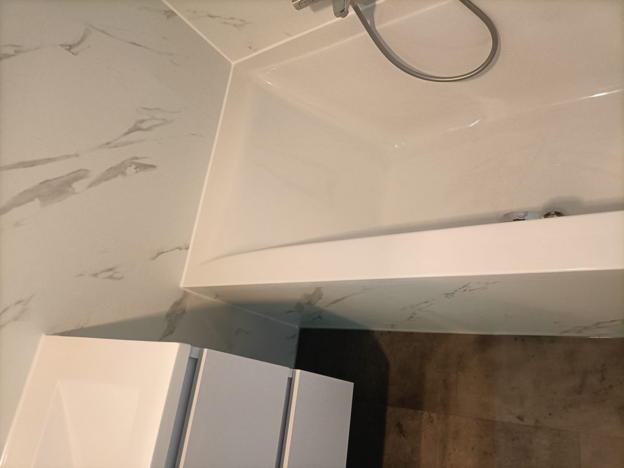 Wit marmeren badkamer met witte douche en betegelde muren