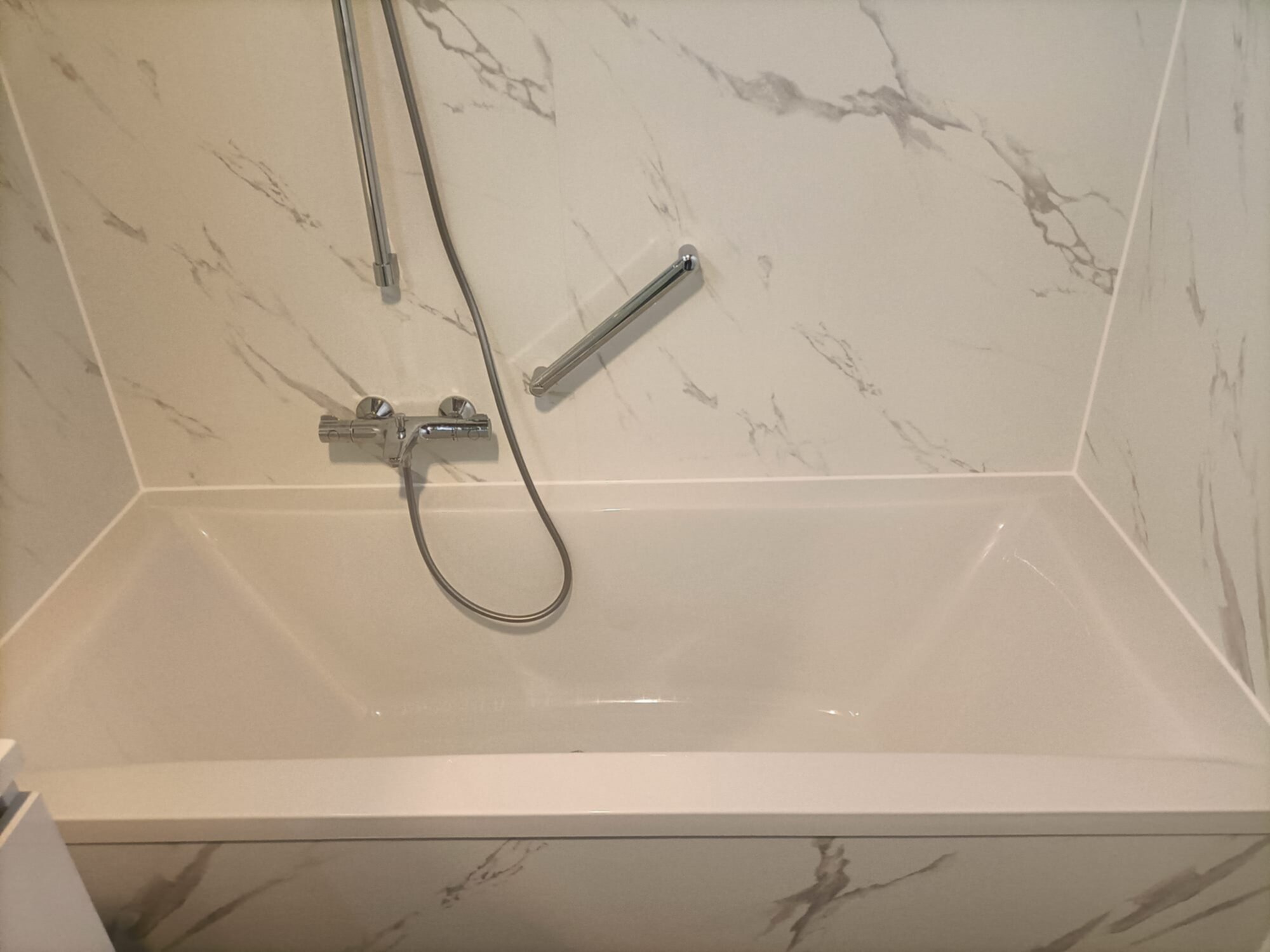 Wit marmeren badkamer met grijze nerven, douche en bad combinatie