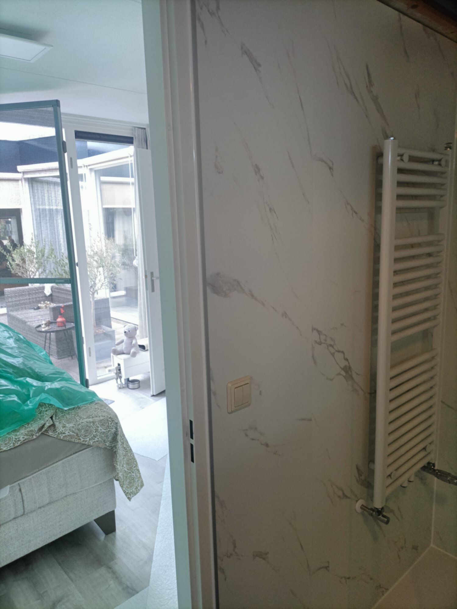 Wit marmeren betegelde muur met verwarmingsradiator in moderne badkamer