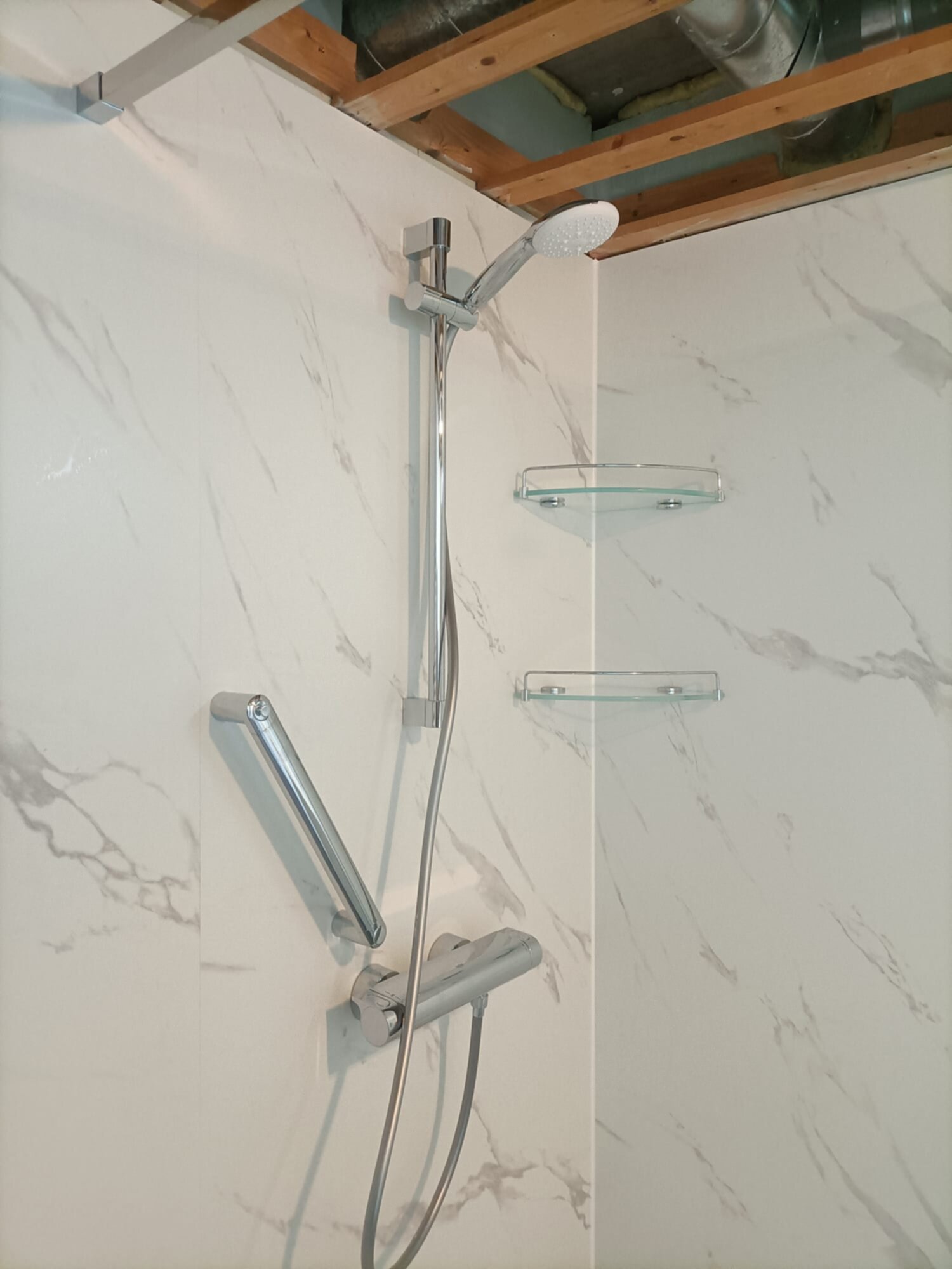 Douche met marmeren tegelwand en moderne chromen douchekraan en -set