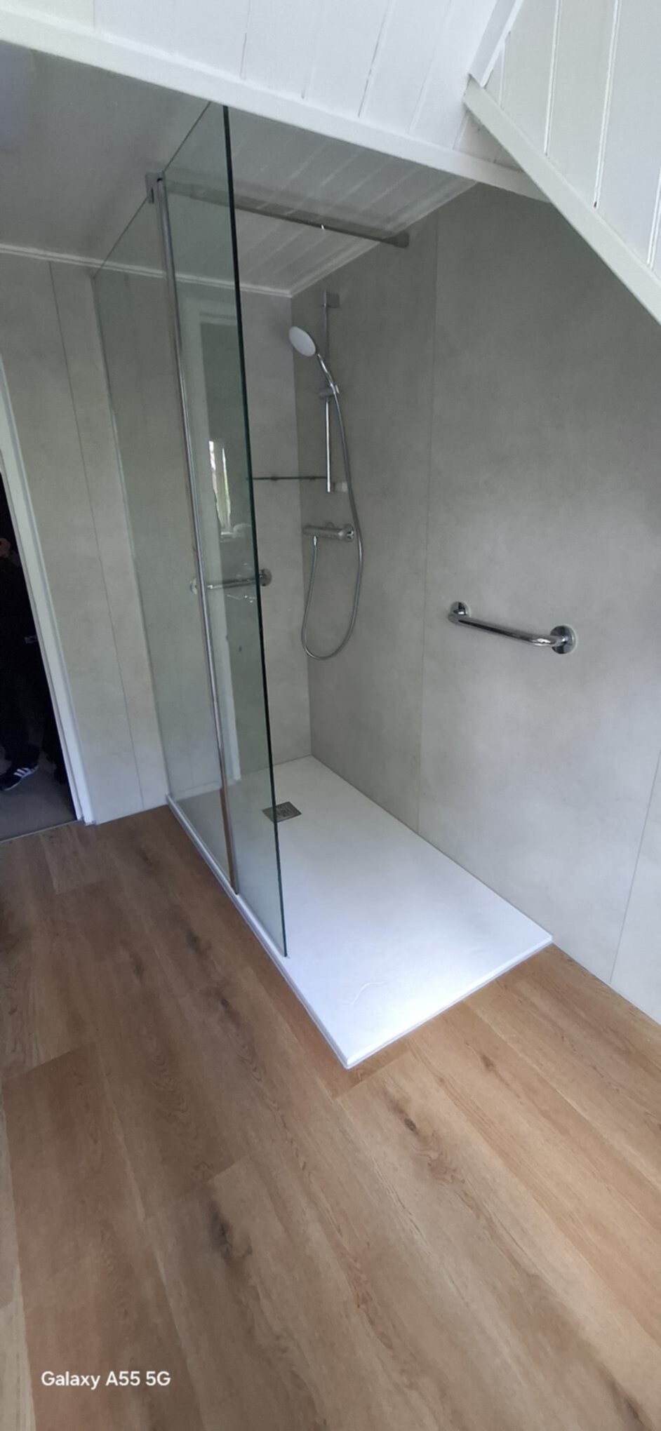 Douchecabine met glazen wand en deur, grijs betegelde wanden en witte douchebak