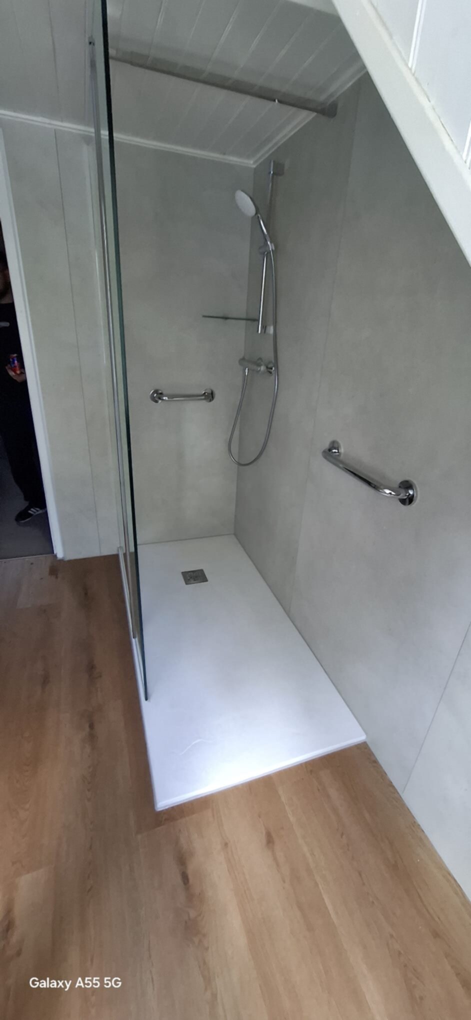 Douchecabine met glazen deur en wand, grijs betegeld met witte douchebak