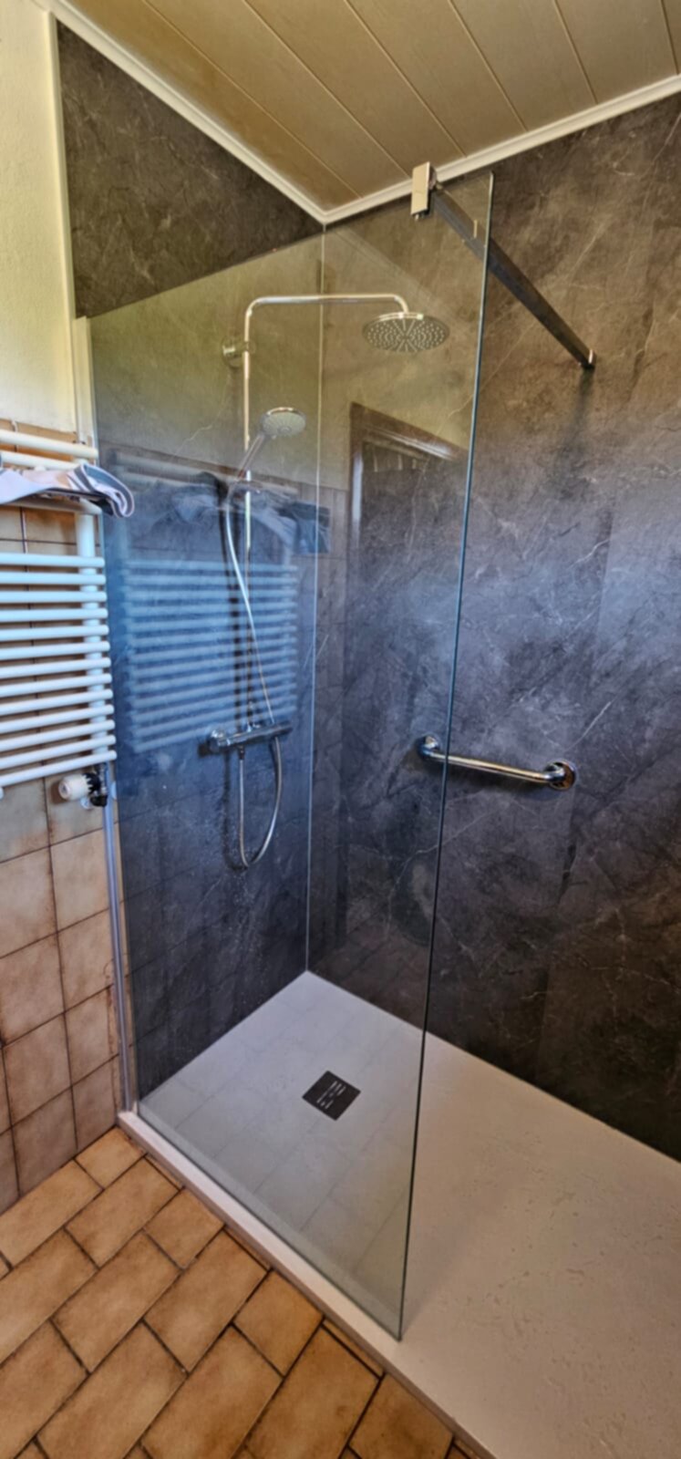 Douchecabine met glazen wand en deur, grijs marmer en witte vloer