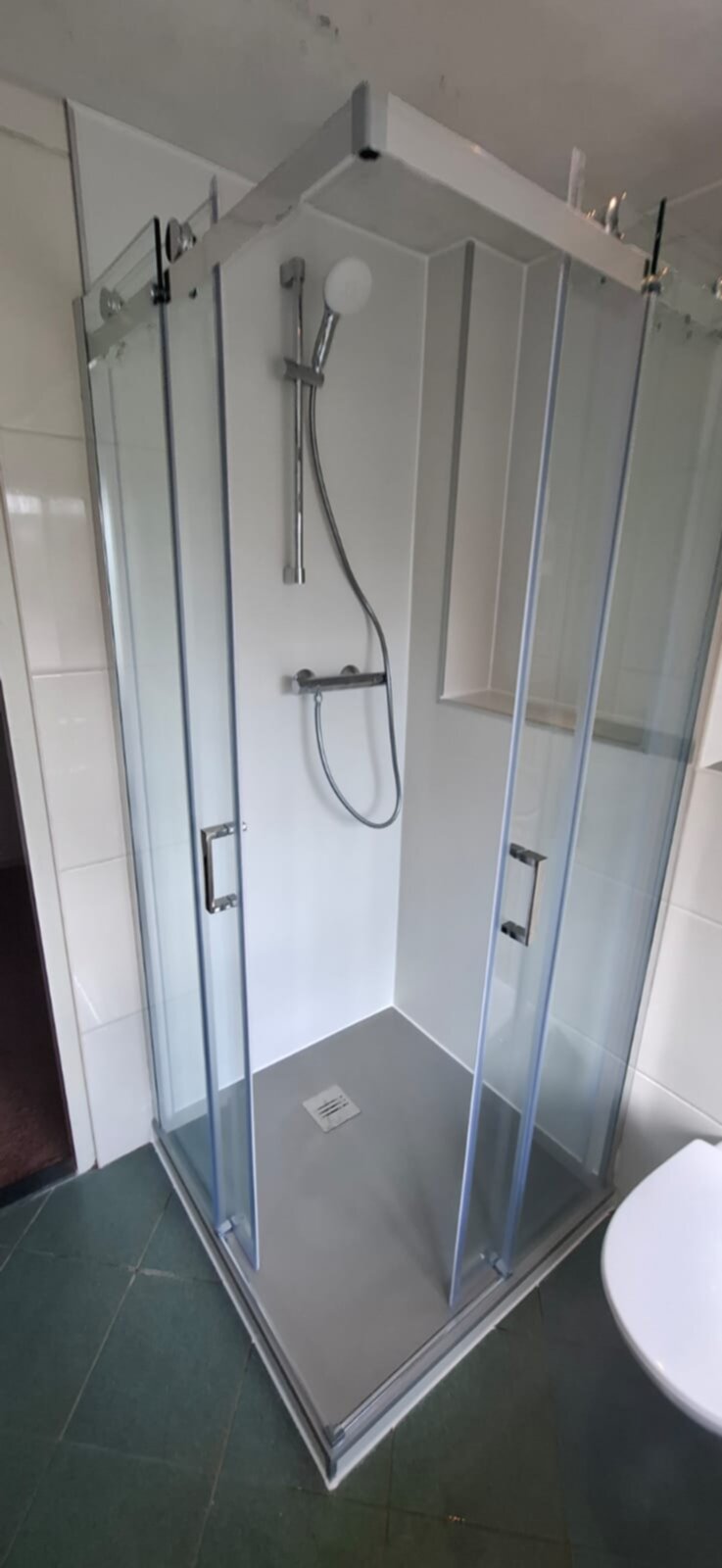 Douchecabine met glazen wanden en een moderne douchekop