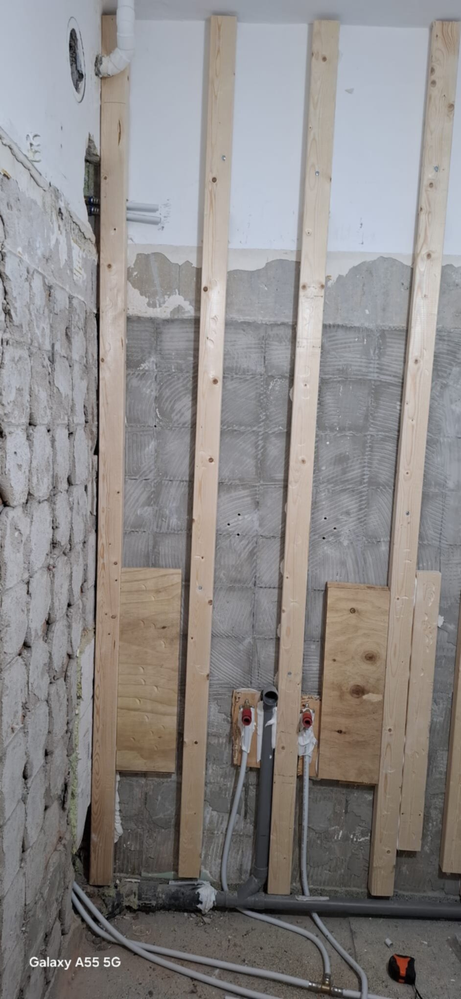 Badkamer renovatie in uitvoering met houten latten en blootgelegde leidingen
