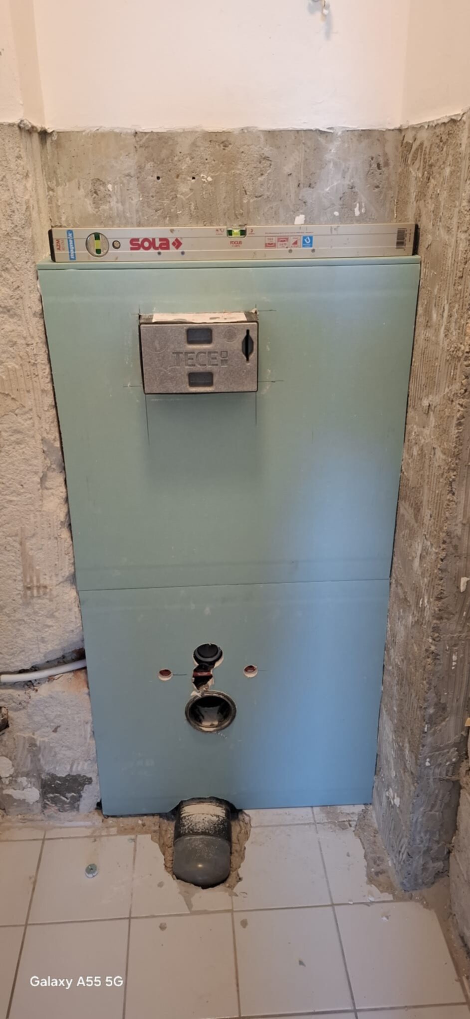 Een groene muur met een metalen kast en een SOLA waterpas erop in een badkamer