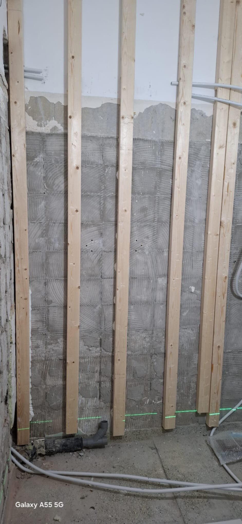 Ontvangersruimte badkamer renovatie met houten latten en blootliggende leidingen