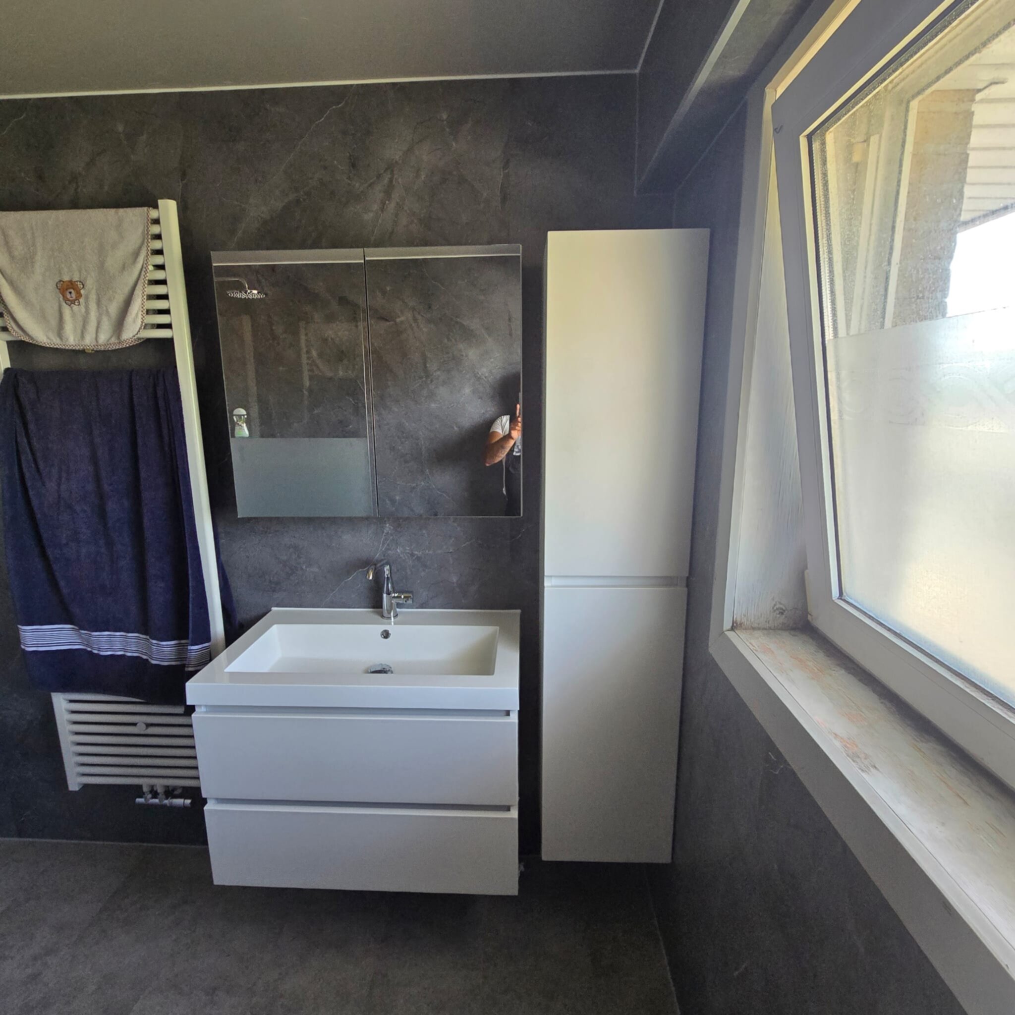 Moderne badkamer met witte wastafel en donkere tegelwanden