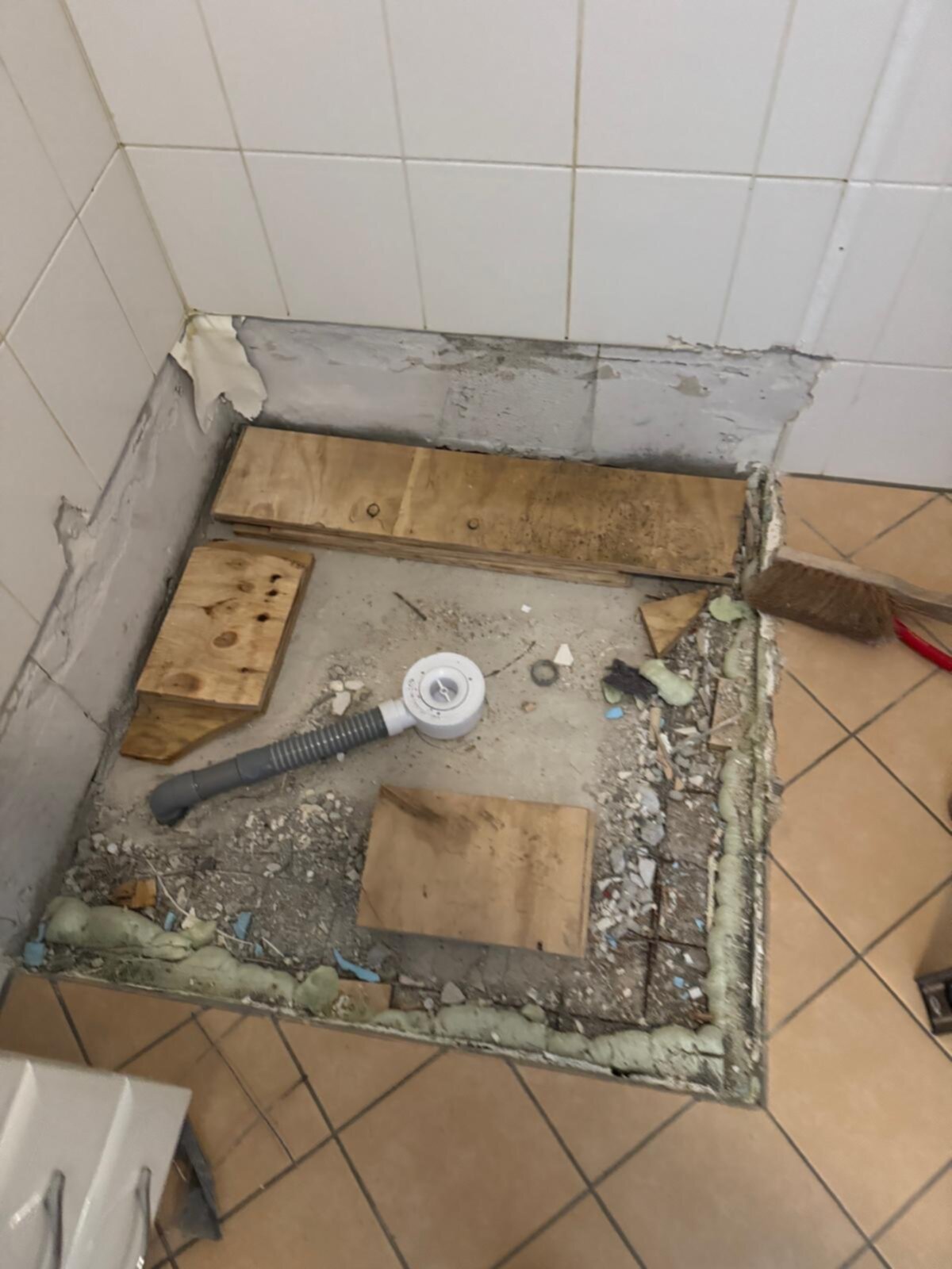 Sloop badkamer met houten planken en afvoerbuis op de grond