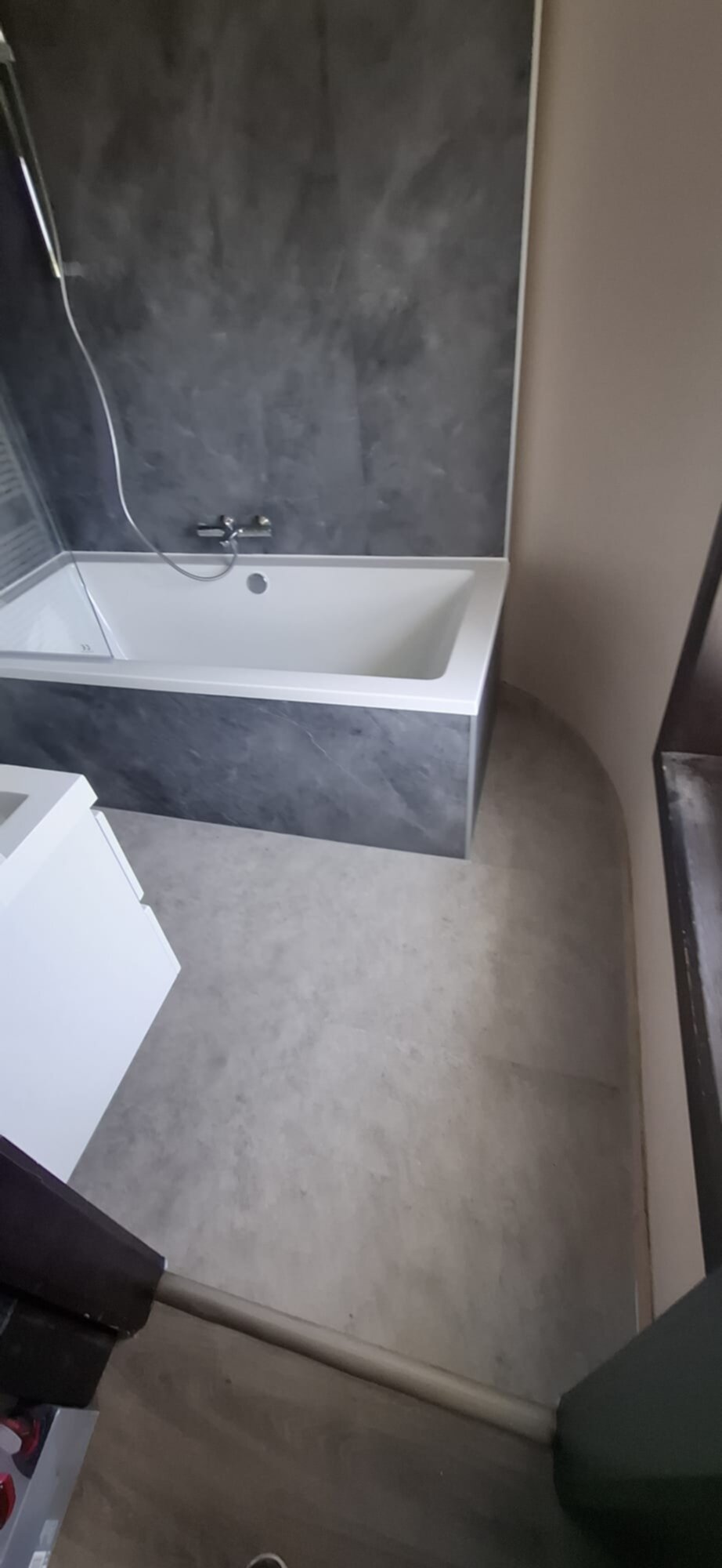 Badkamer met witte badkuip en grijze tegelwand