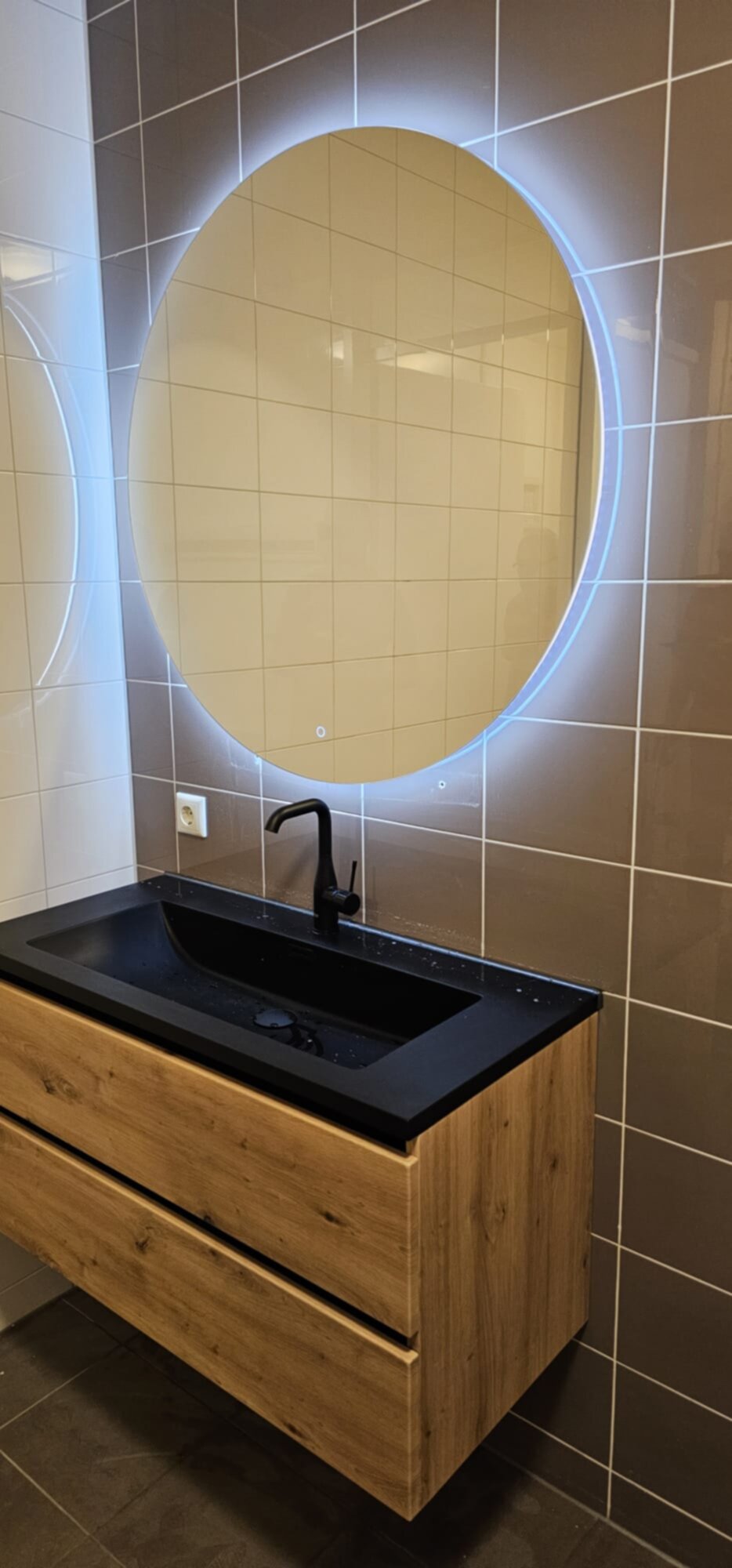 Moderne badkamer met houten wastafel en verlicht ronde spiegel