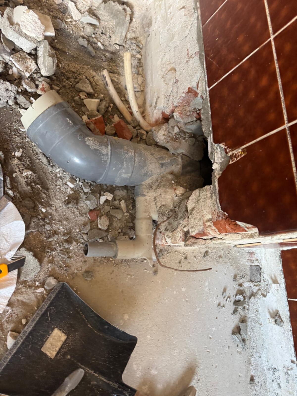 Sloopwerk badkamer met zicht op de rioleringsbuizen en kapotte tegelvloer
