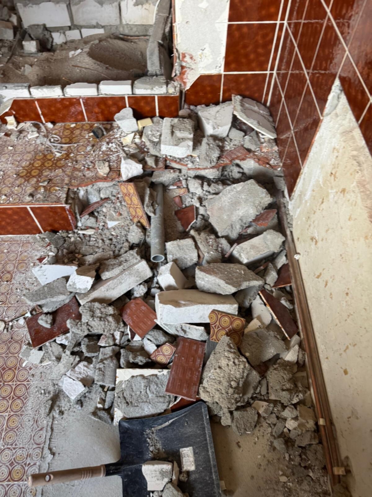 Verwijderde betegeling en puin in badkamer tijdens renovatie