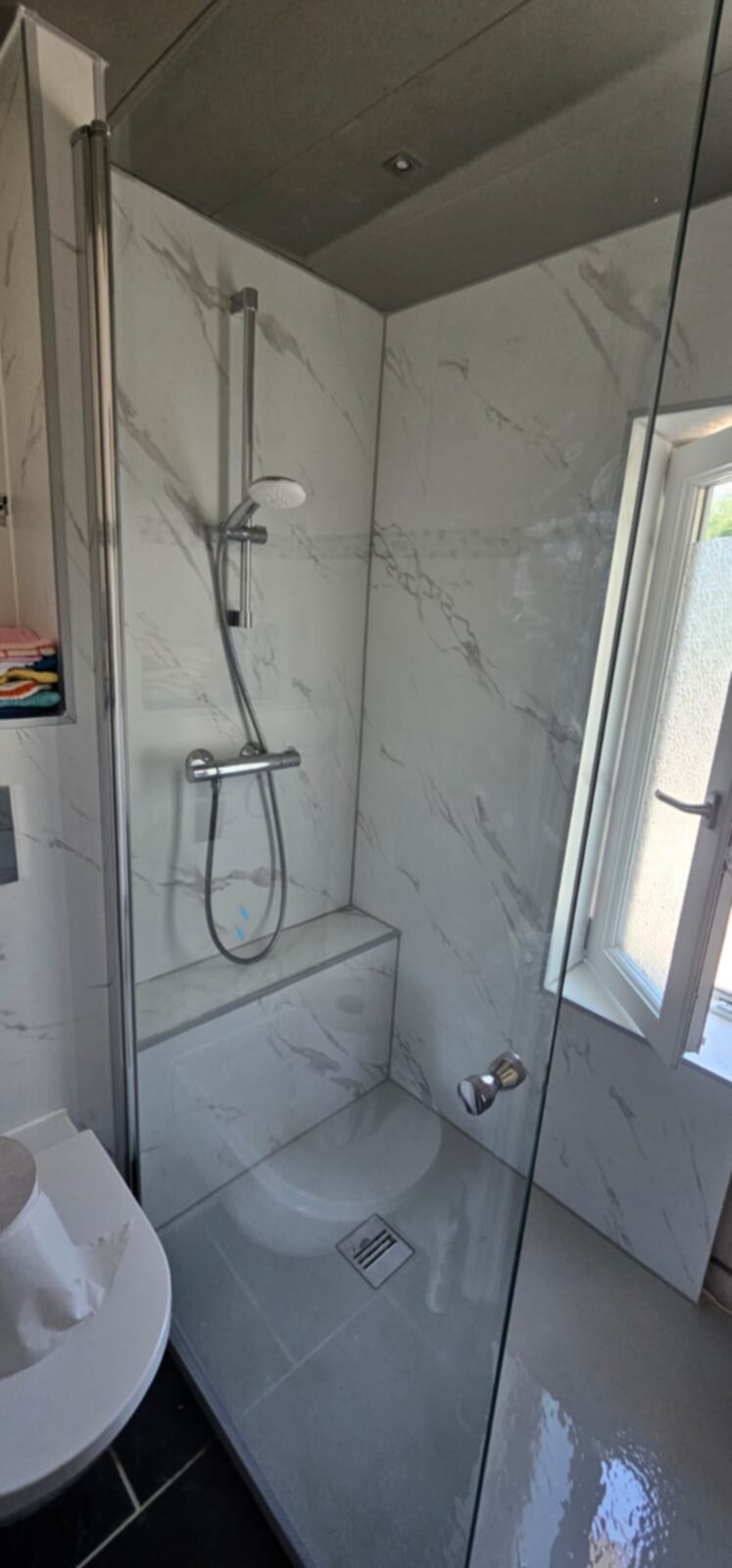 Douchecabine met marmerlook tegels en glazen deur in moderne badkamer