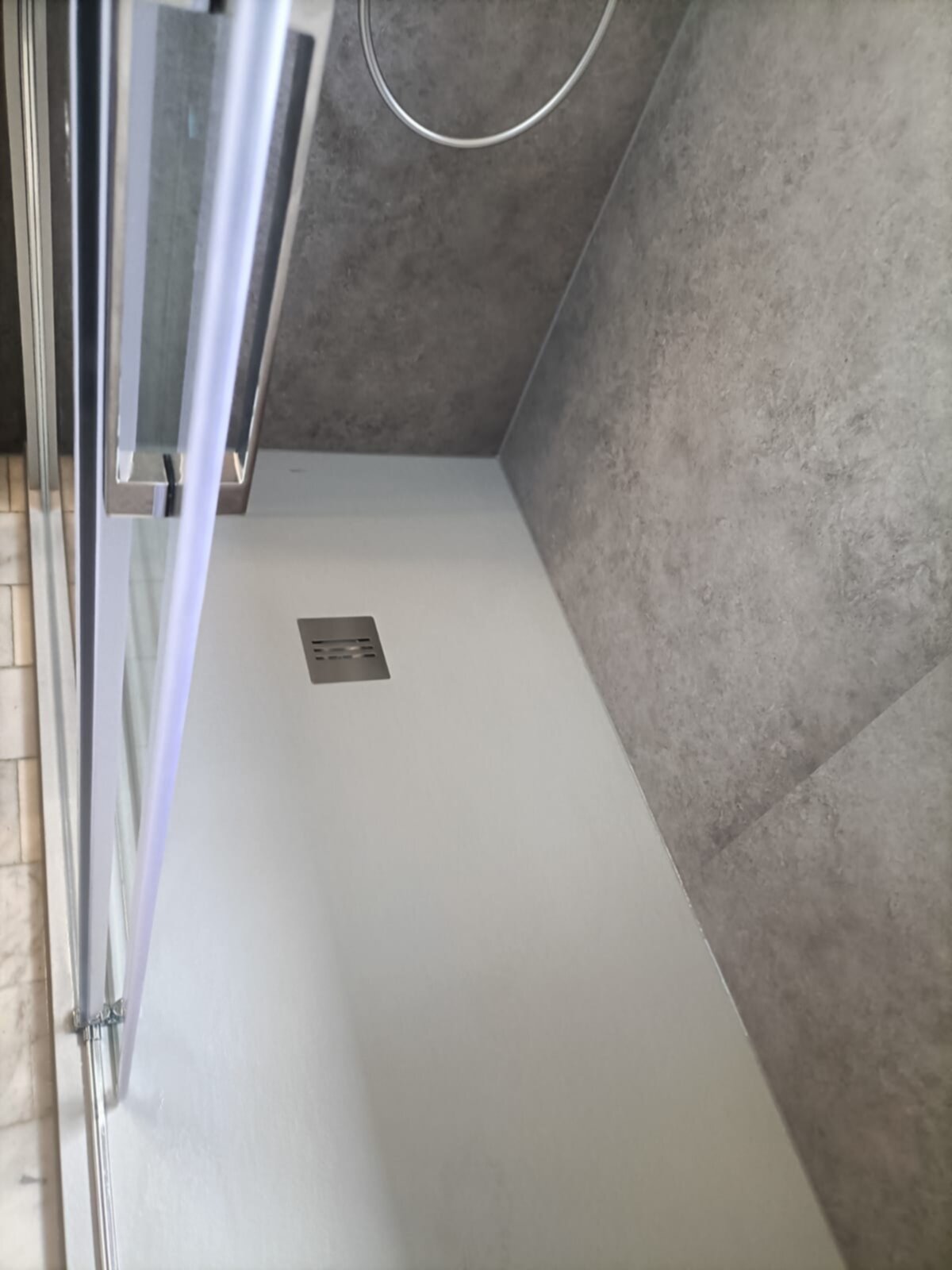 Douche ruimte met grijze wandtegels en witte vloer