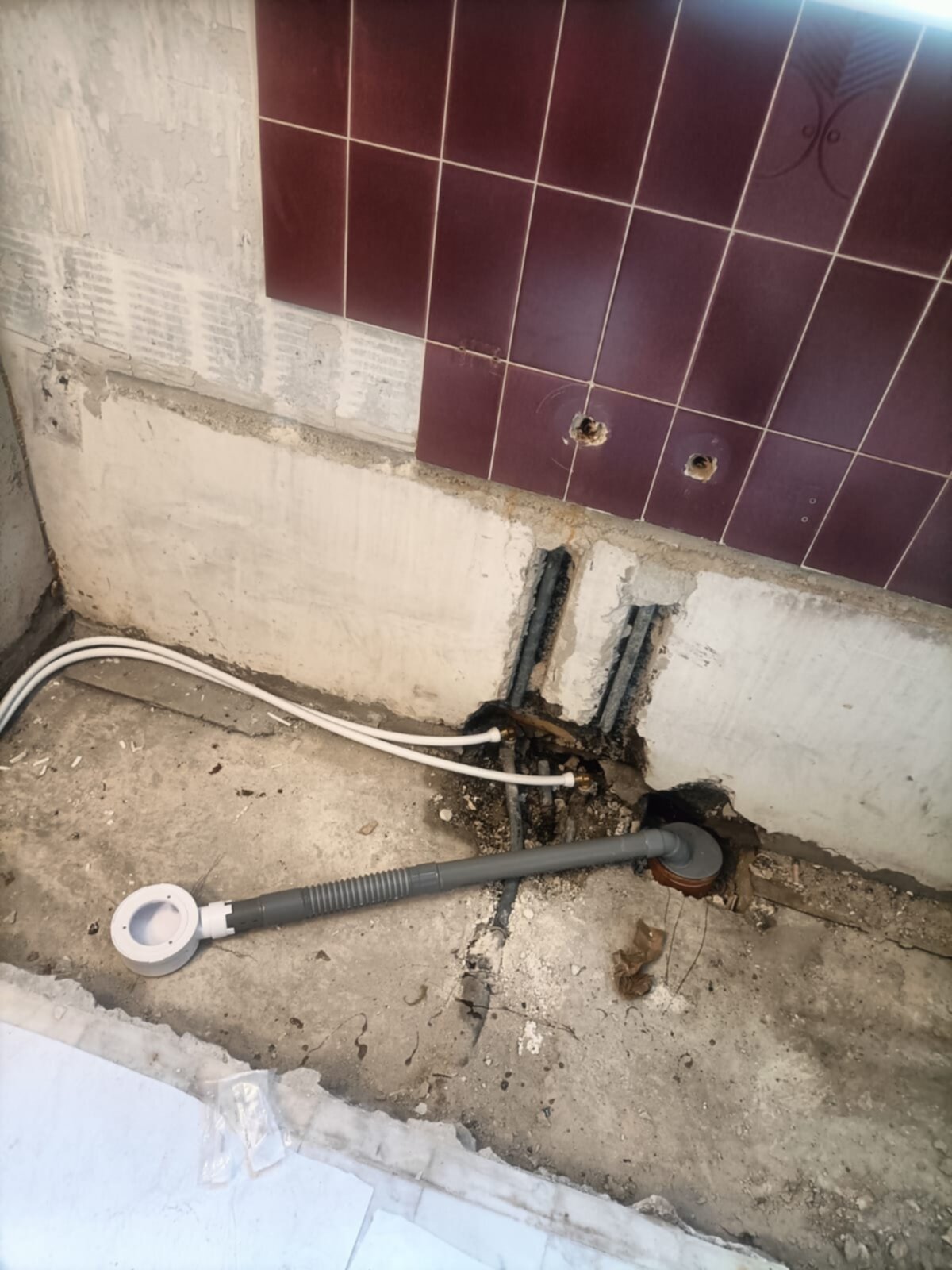 Sleuf in de badkamer vloer met blootgelegde leidingen en rioleringsbuis
