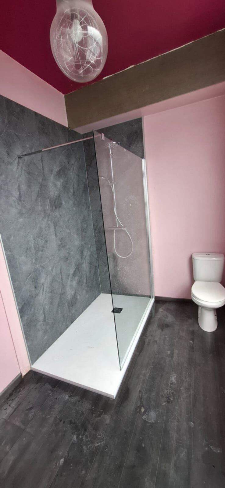 Douchecabine met glazen wand en roze en grijze muren