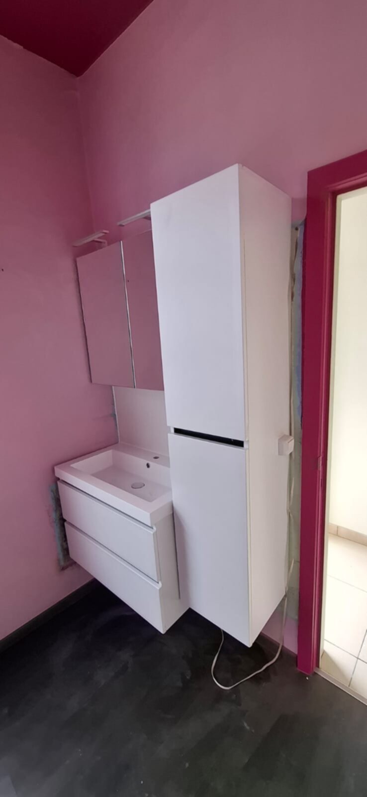 Wit betegelde badkamer met wasbak en kast in renovatie fase