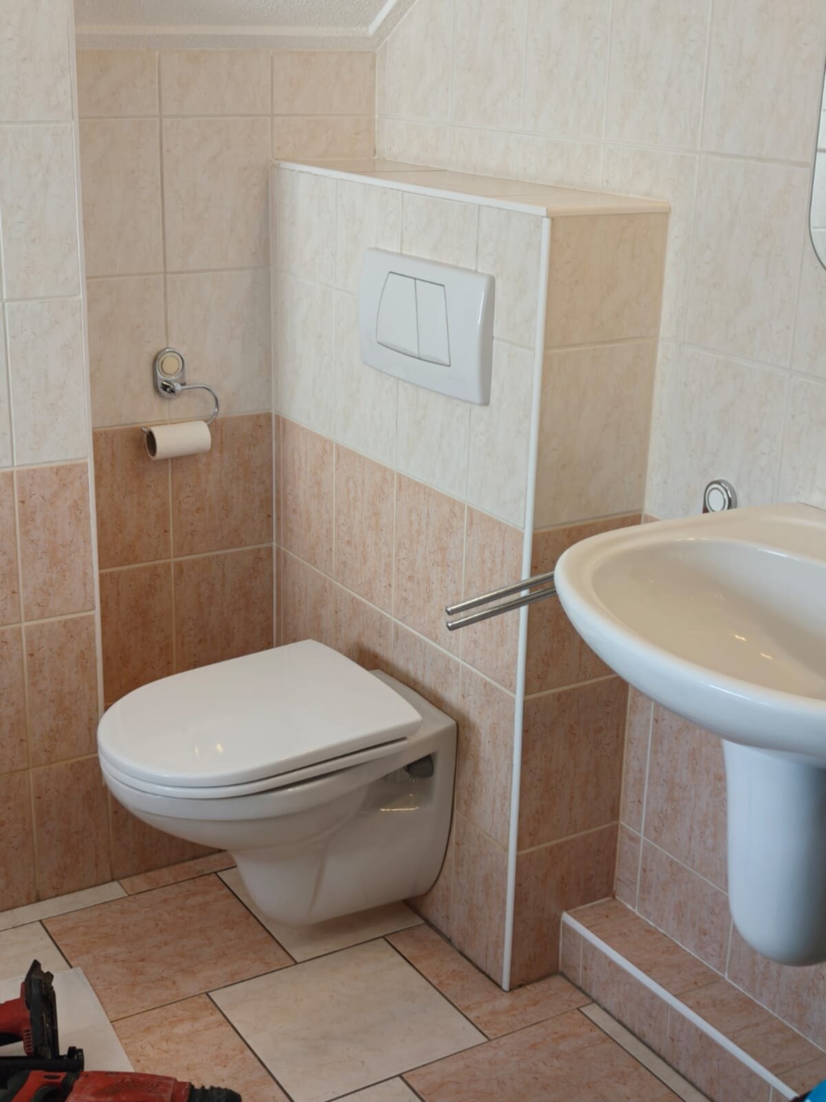 Wit toilet en wasbak in badkamer met beige en bruine tegels