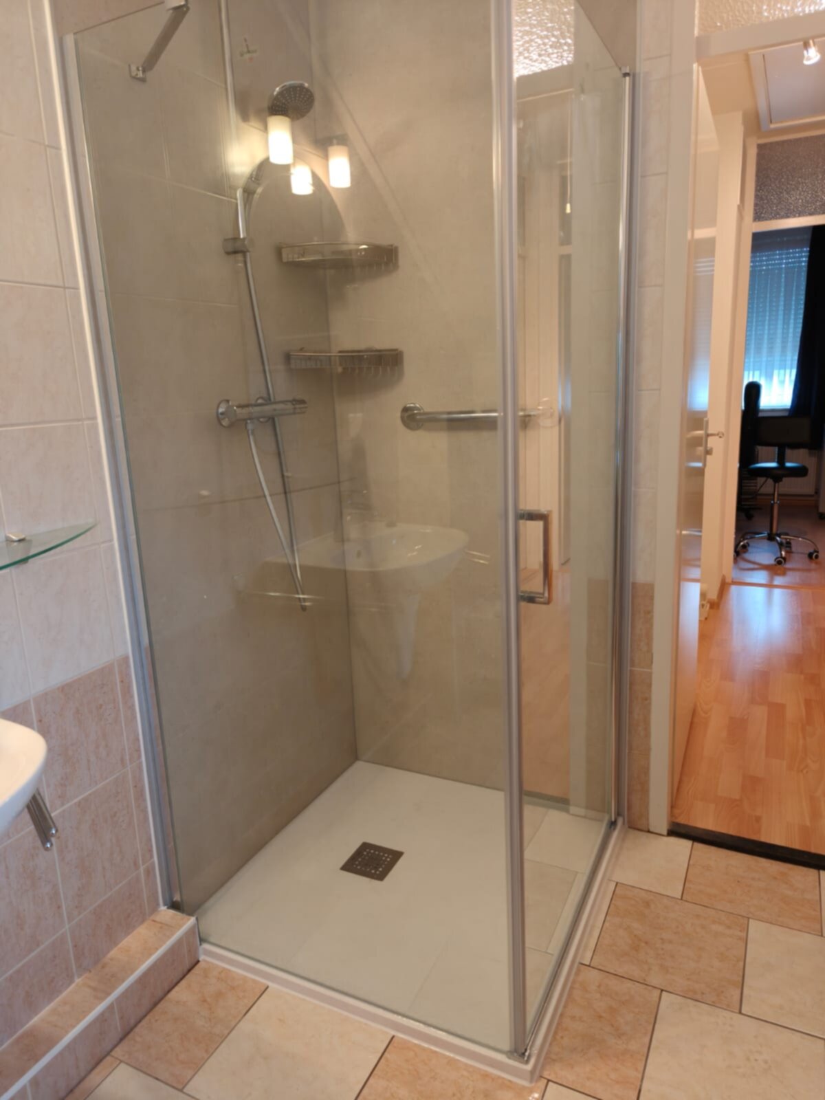 Douchecabine met glazen deur en wand, chroom en beige betegeling