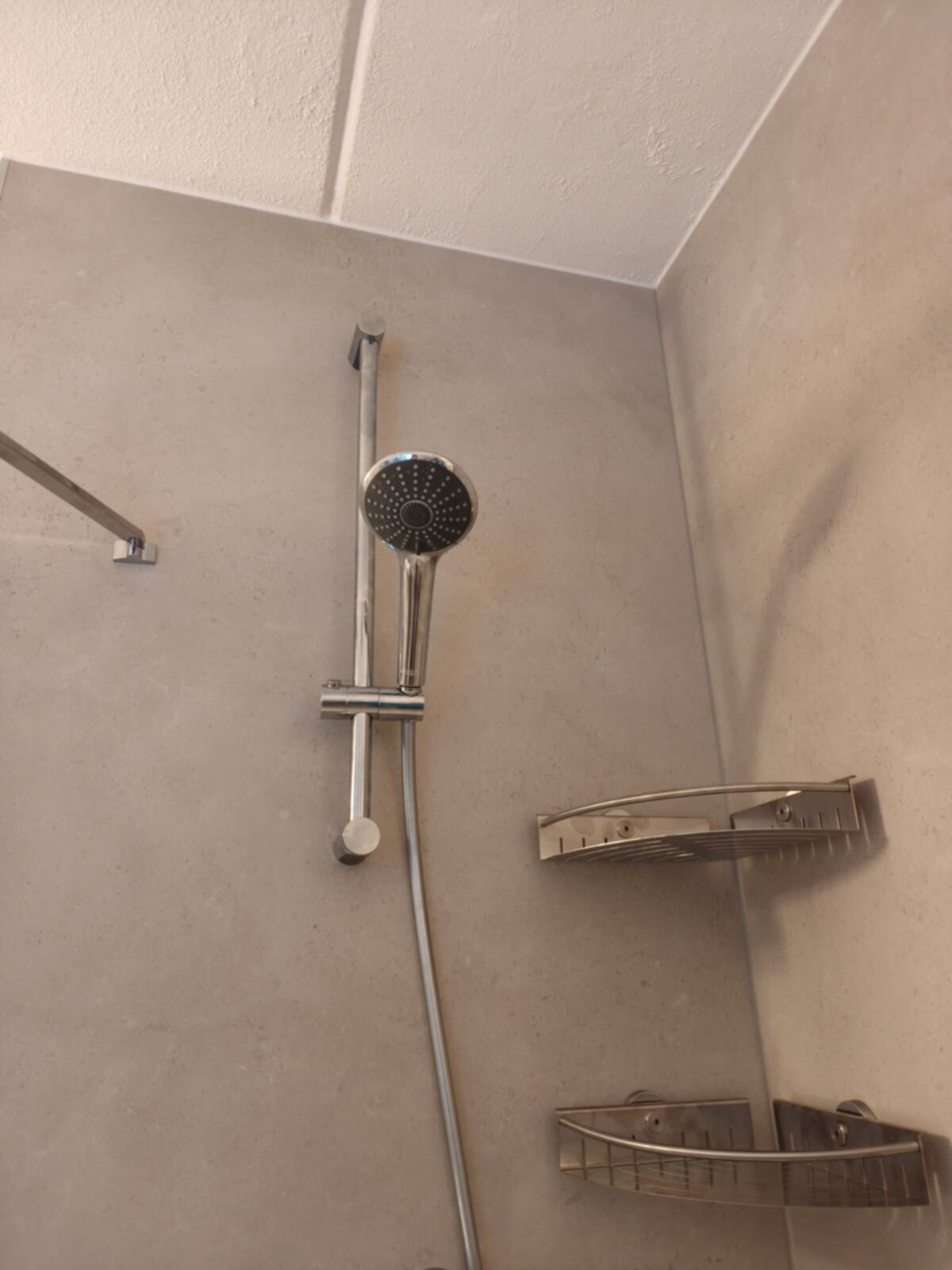 Douche met grijze wanden en chroom douchekraan en -planken