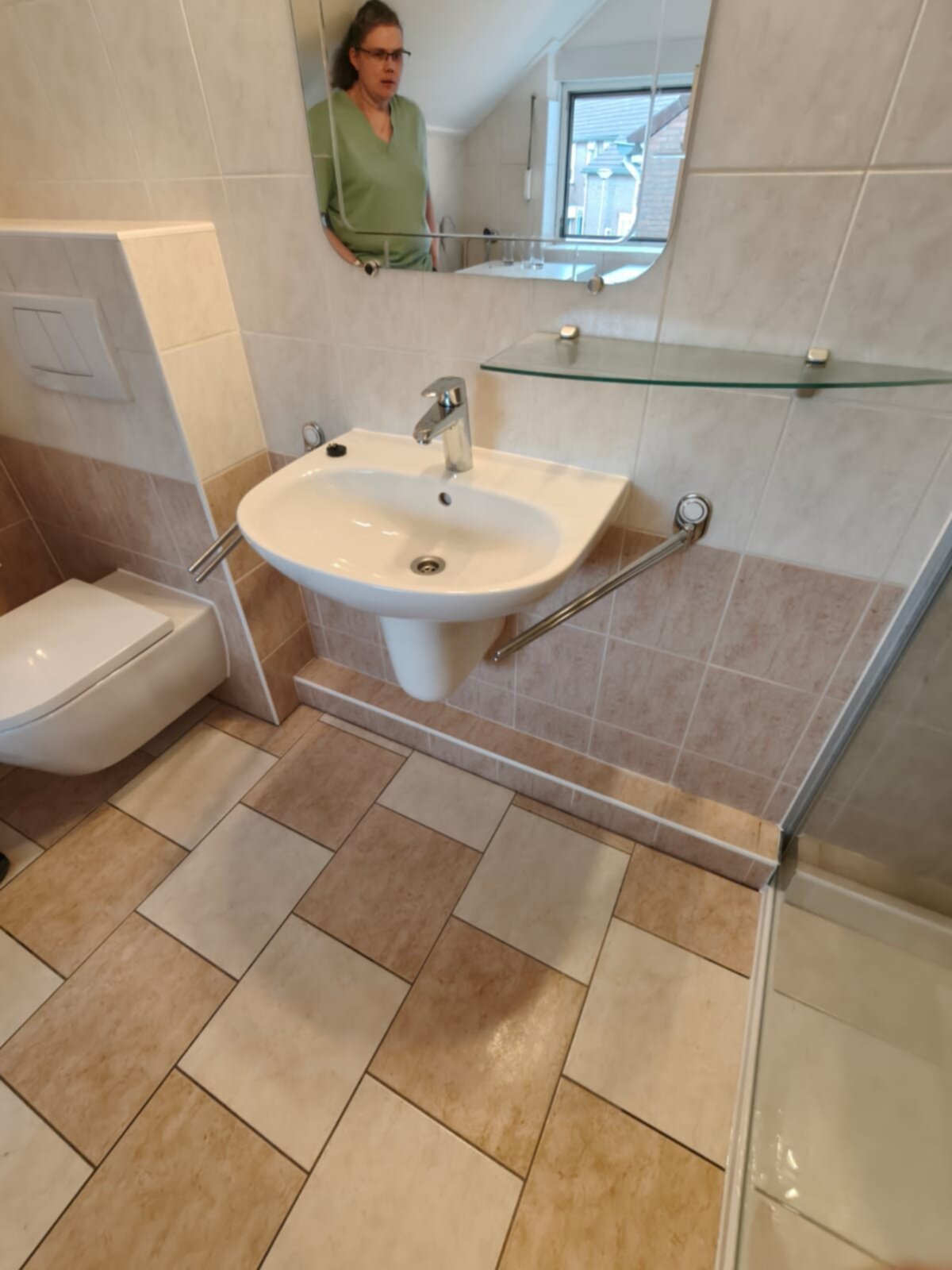 Wit betegelde badkamer met beige en bruine vloer, toilet, wastafel en glazen schap