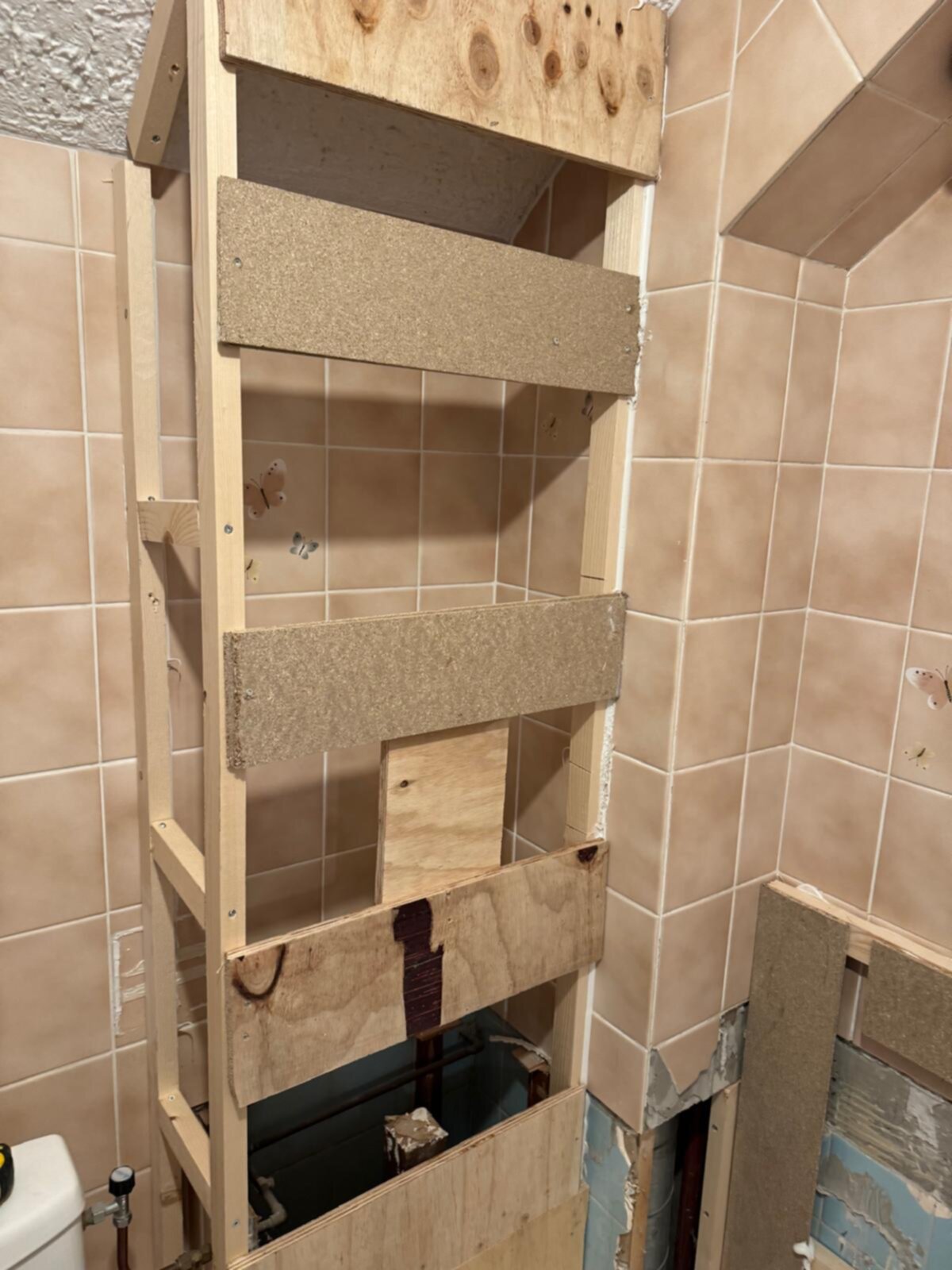 Ontvangst badkamer renovatie, betegelde wand met houten constructie voor nieuwe inbouw