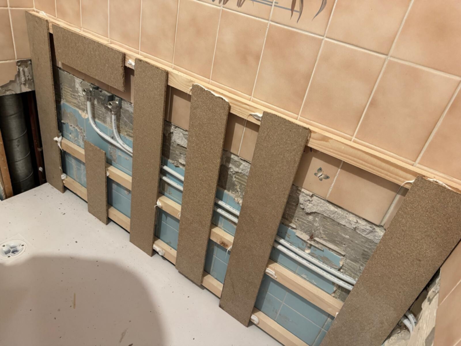 Badkamer renovatie, betegelde wand met openingen en bruine platen