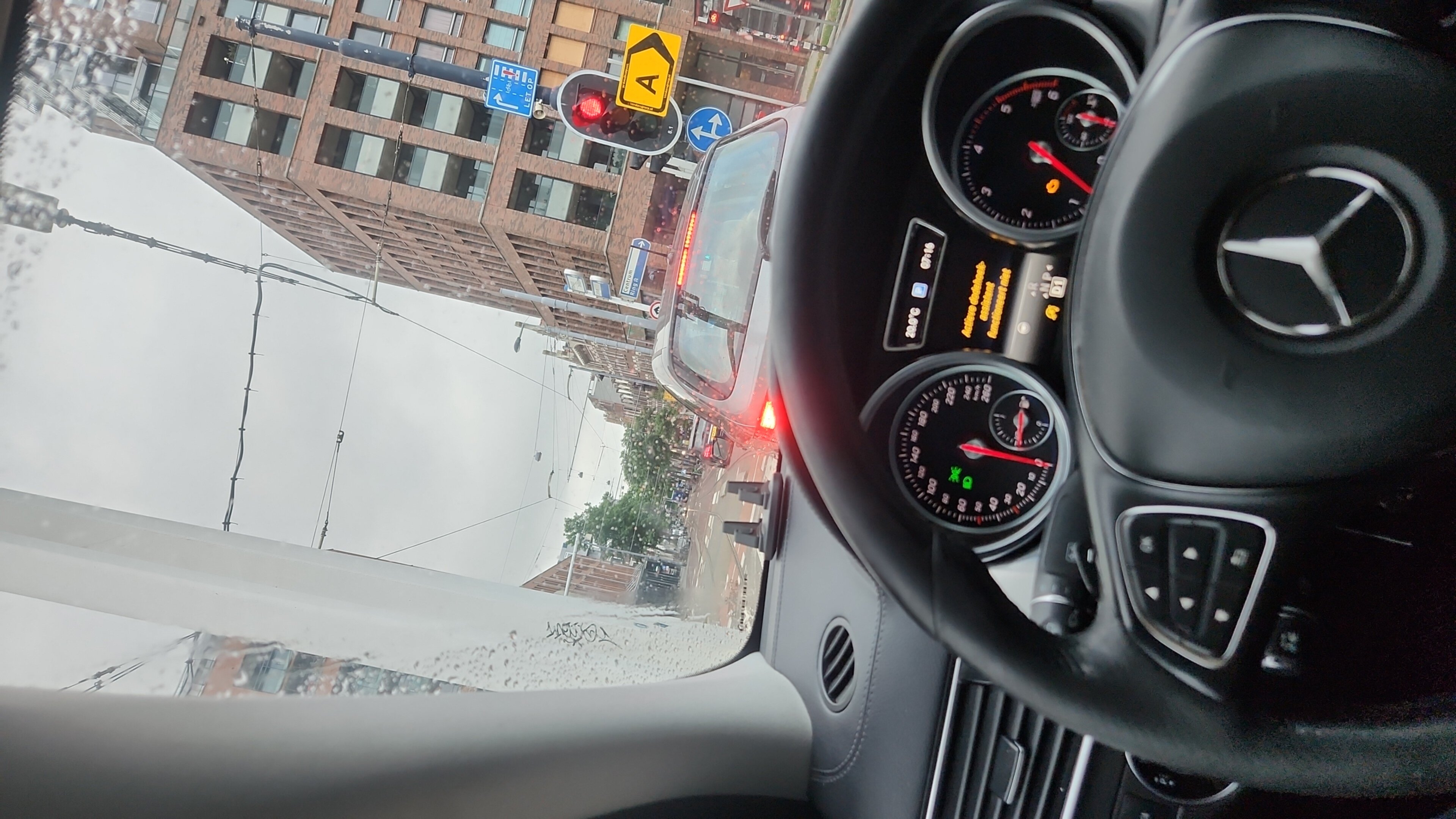 Mercedes dashboard met stuurwiel en instrumenten tijdens het rijden in de regen