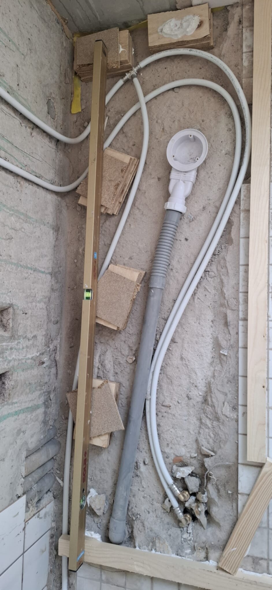 Blootgelegde leidingen en rioleringsbuis in badkamer tijdens renovatie