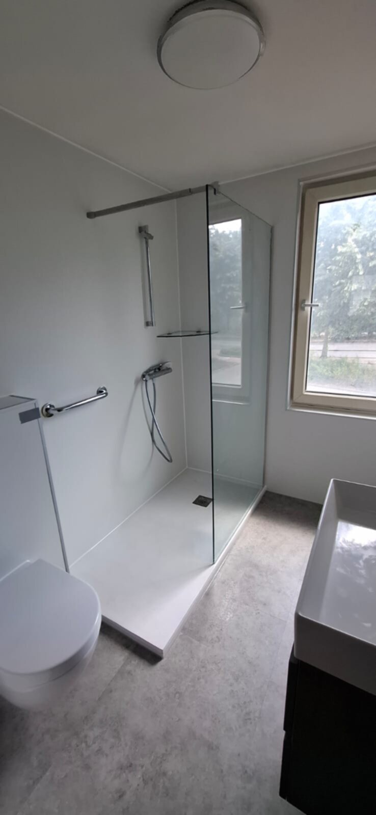 Moderne badkamer met witte tegel, glazen douchecabine en grijs graniet