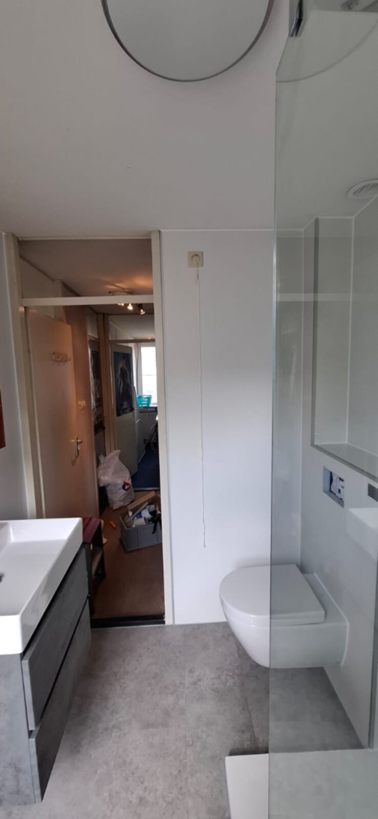 Wit toilet en douche in moderne badkamer met grijze vloer en betegelde wand
