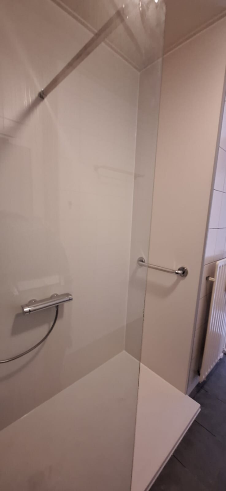 Douchecabine met glazen deur en witte tegelwanden