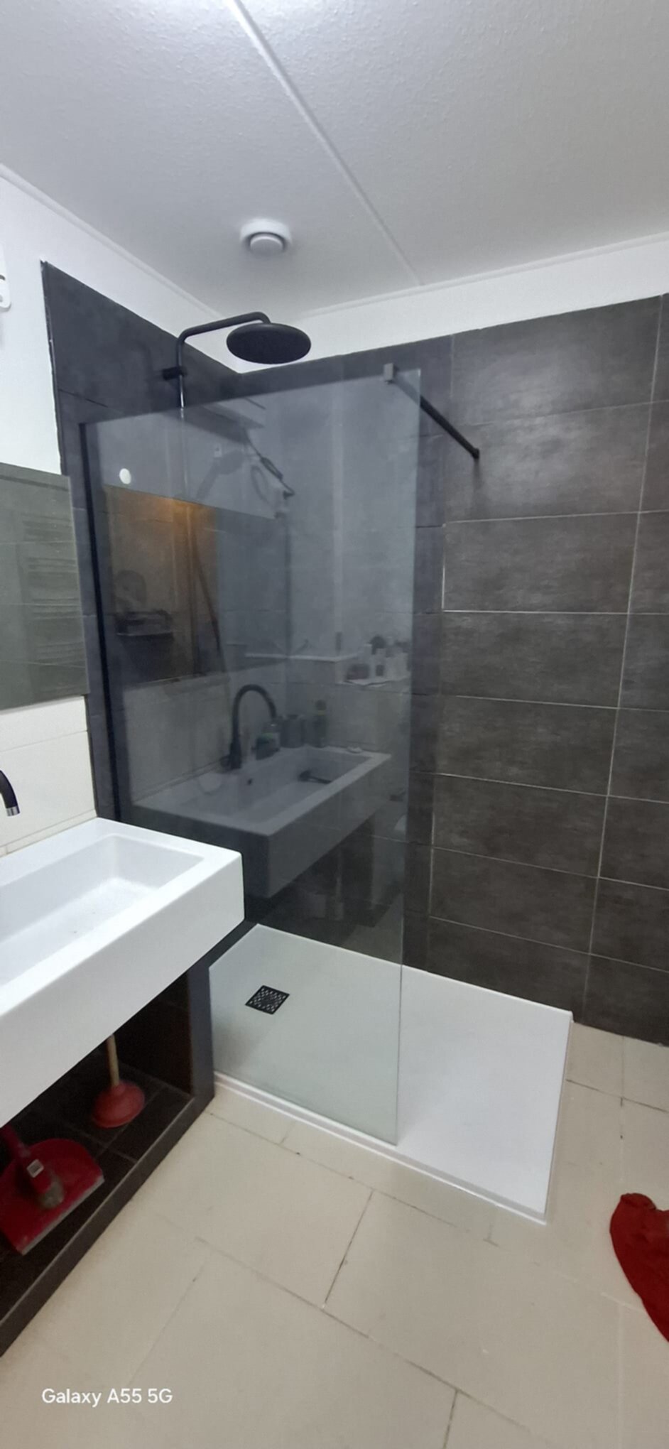 Moderne badkamer met grijze tegels en glazen douchecabine