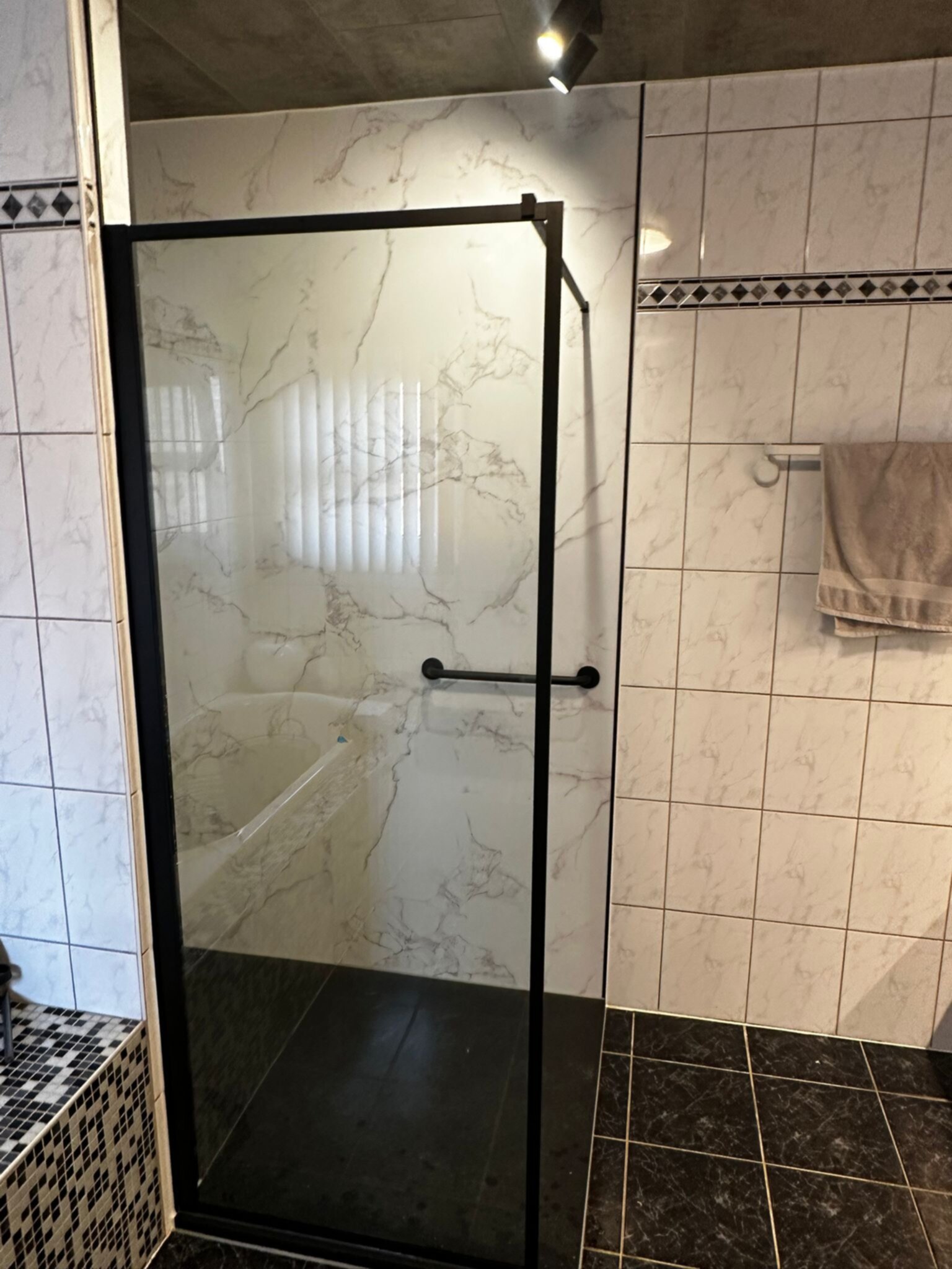 Douchecabine met glazen deur en marmerlook tegels in badkamer