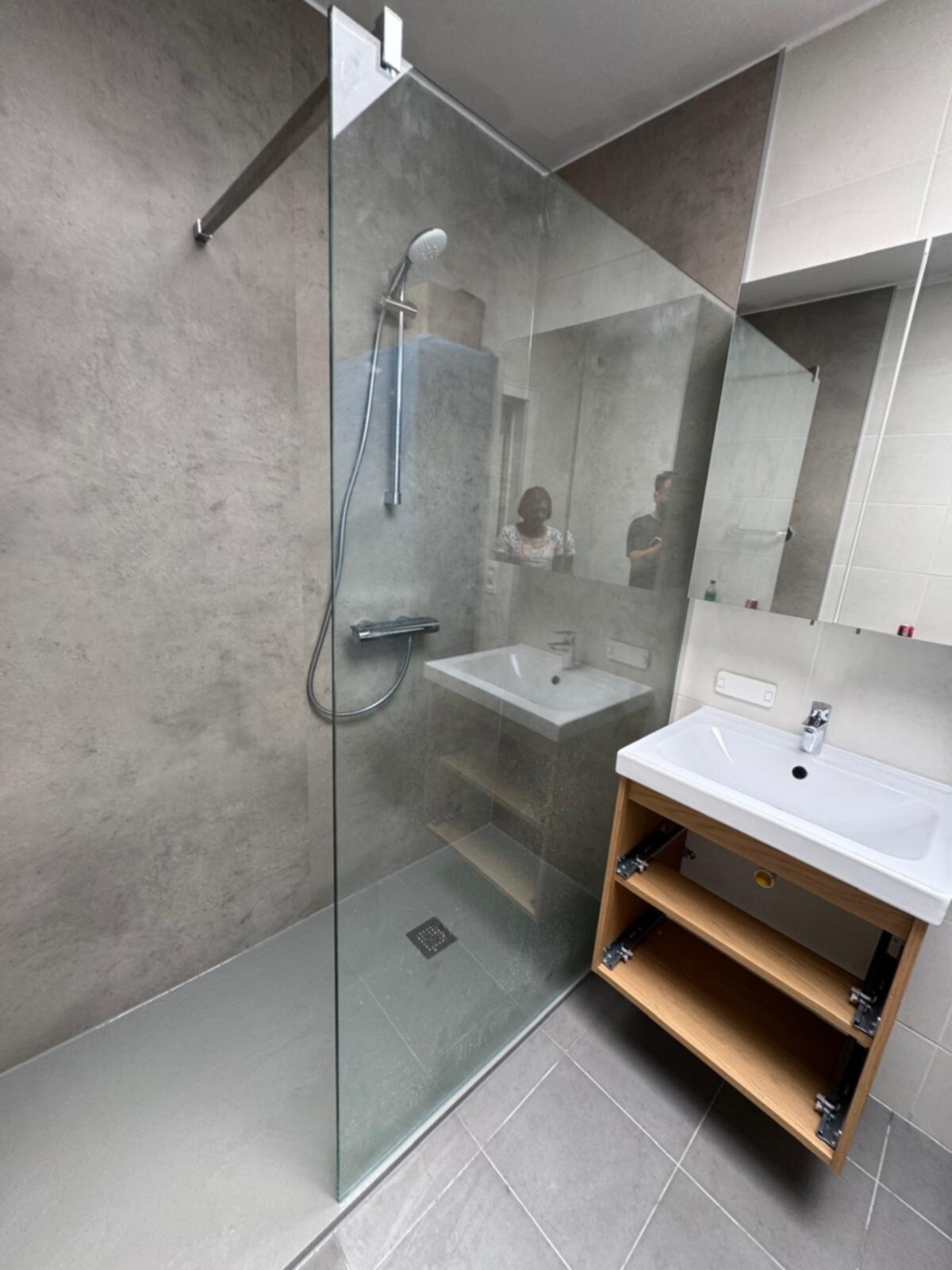 Moderne badkamer met glazen douchecabine en witte wasbak op houten kast