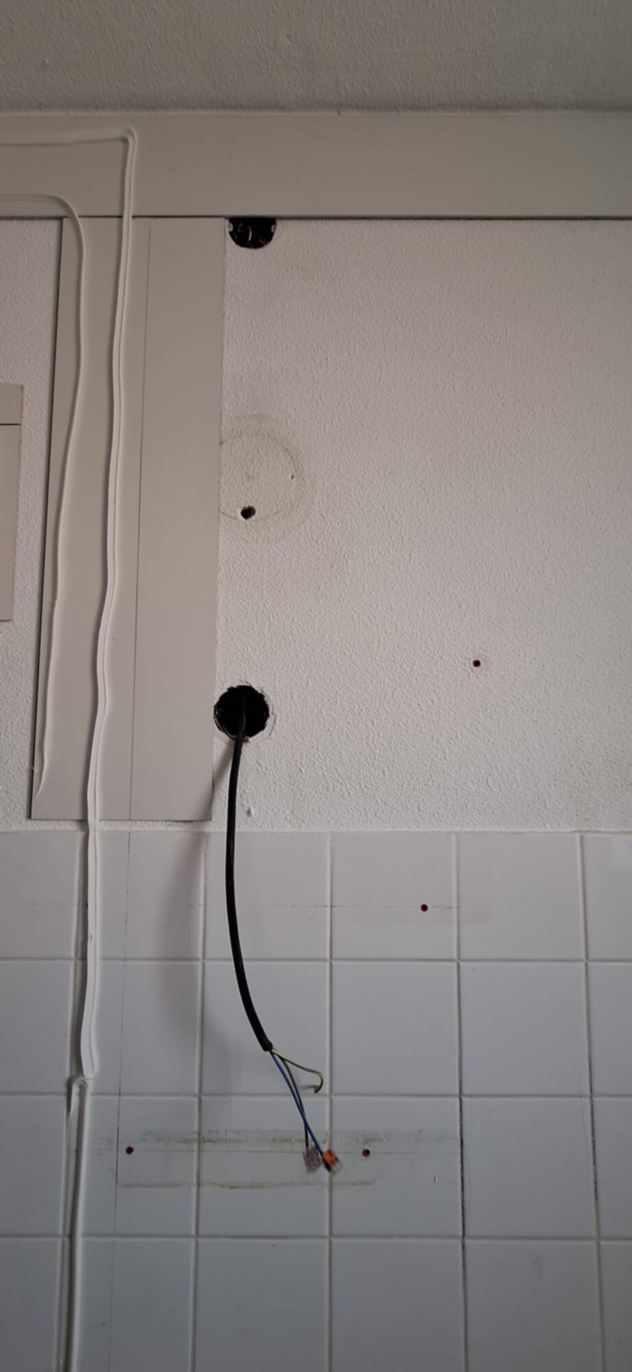 Wit betegelde badkamerwand met gaten voor nieuwe installaties