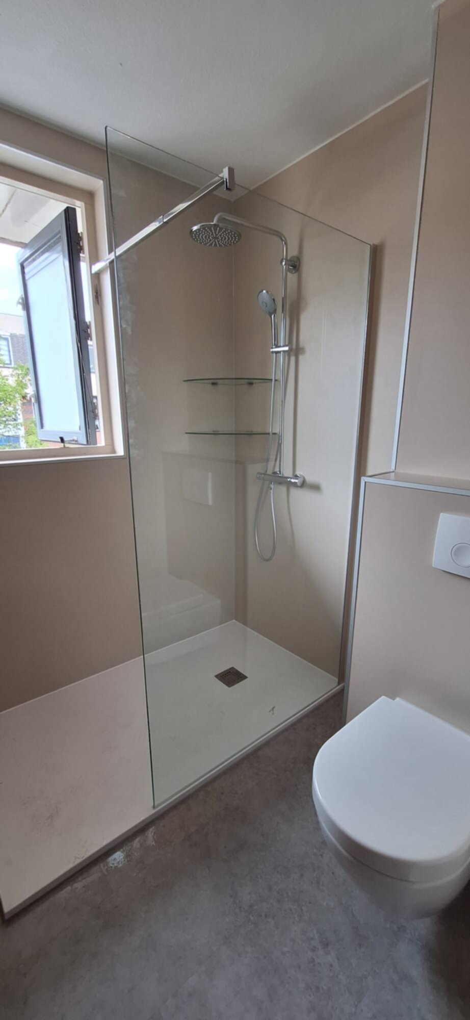 Douchecabine met glazen wand en deur, toilet en betegelde muren in beige en grijs