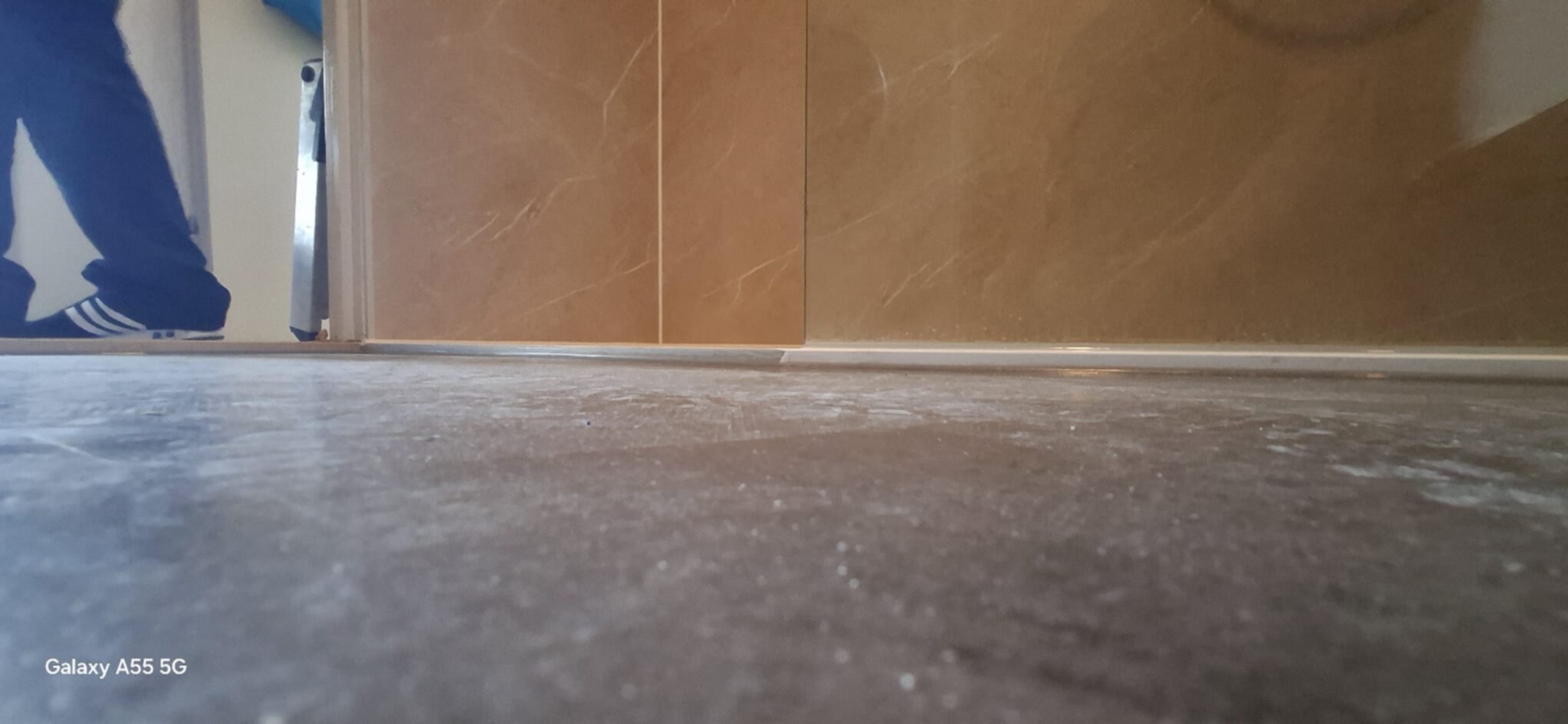 Grijze beton vloer met persoon in de achtergrond en bruine marmer wand