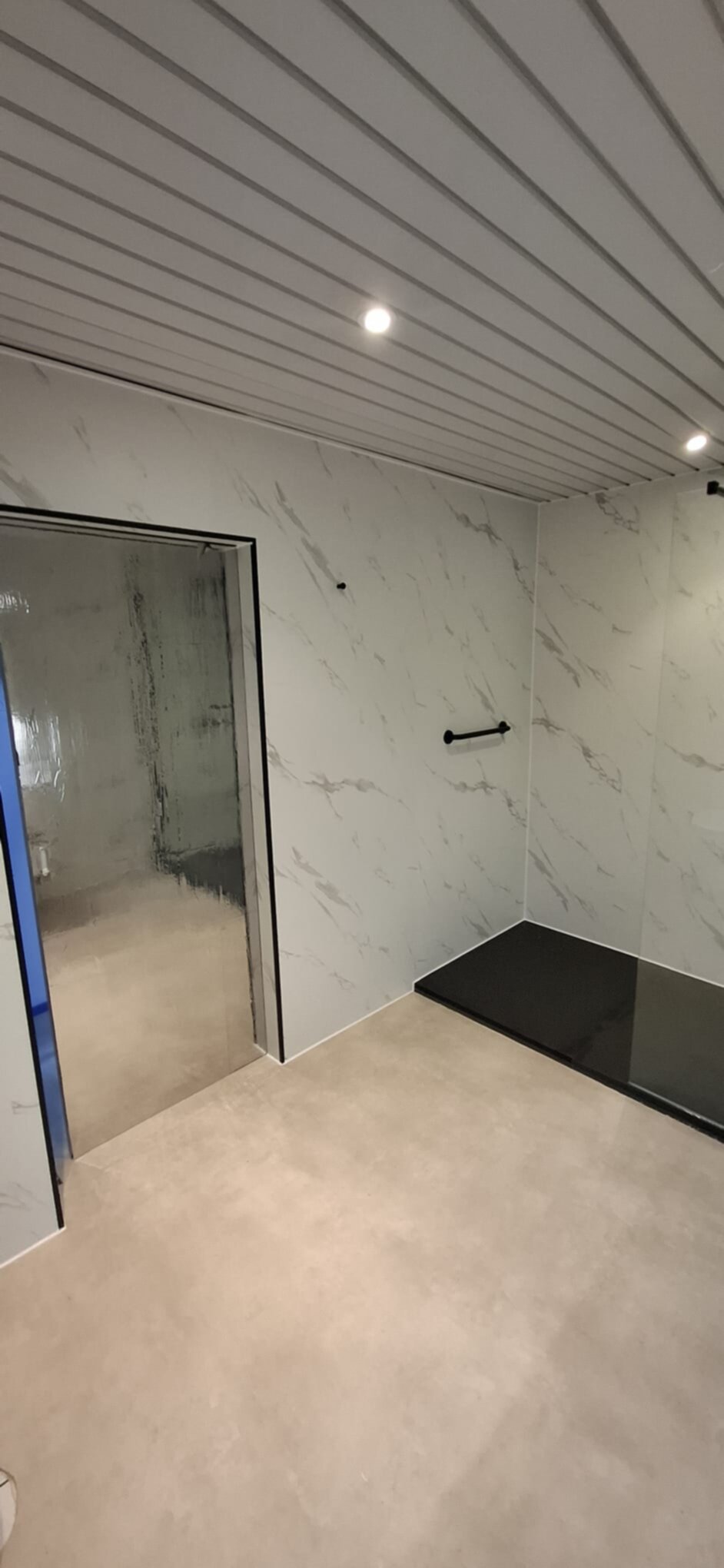 Marmeren badkamer met witte en grijze marmerlook tegels en zwarte douchebak