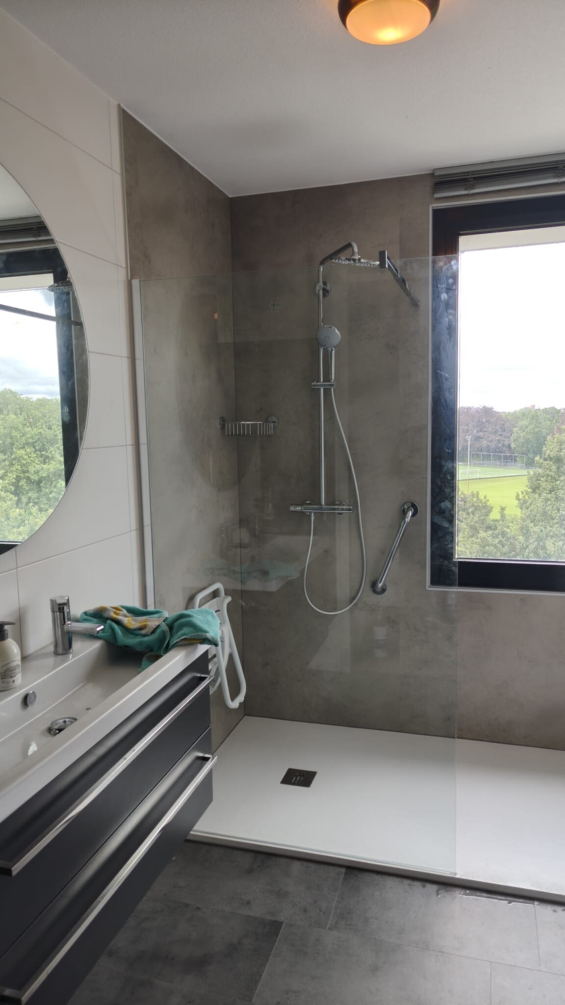 Moderne badkamer met grijze tegels, douche en wastafel